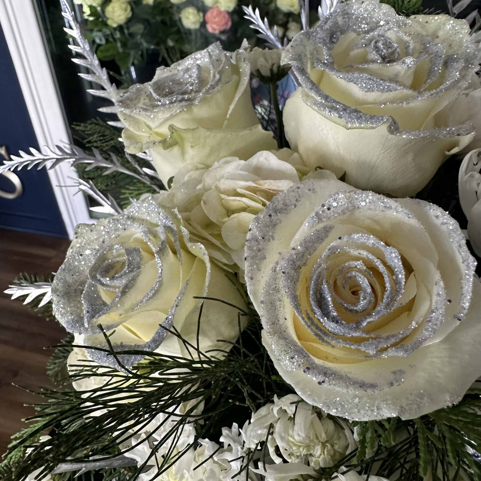 Cream roses with silver glitter accents in a floral arrangement