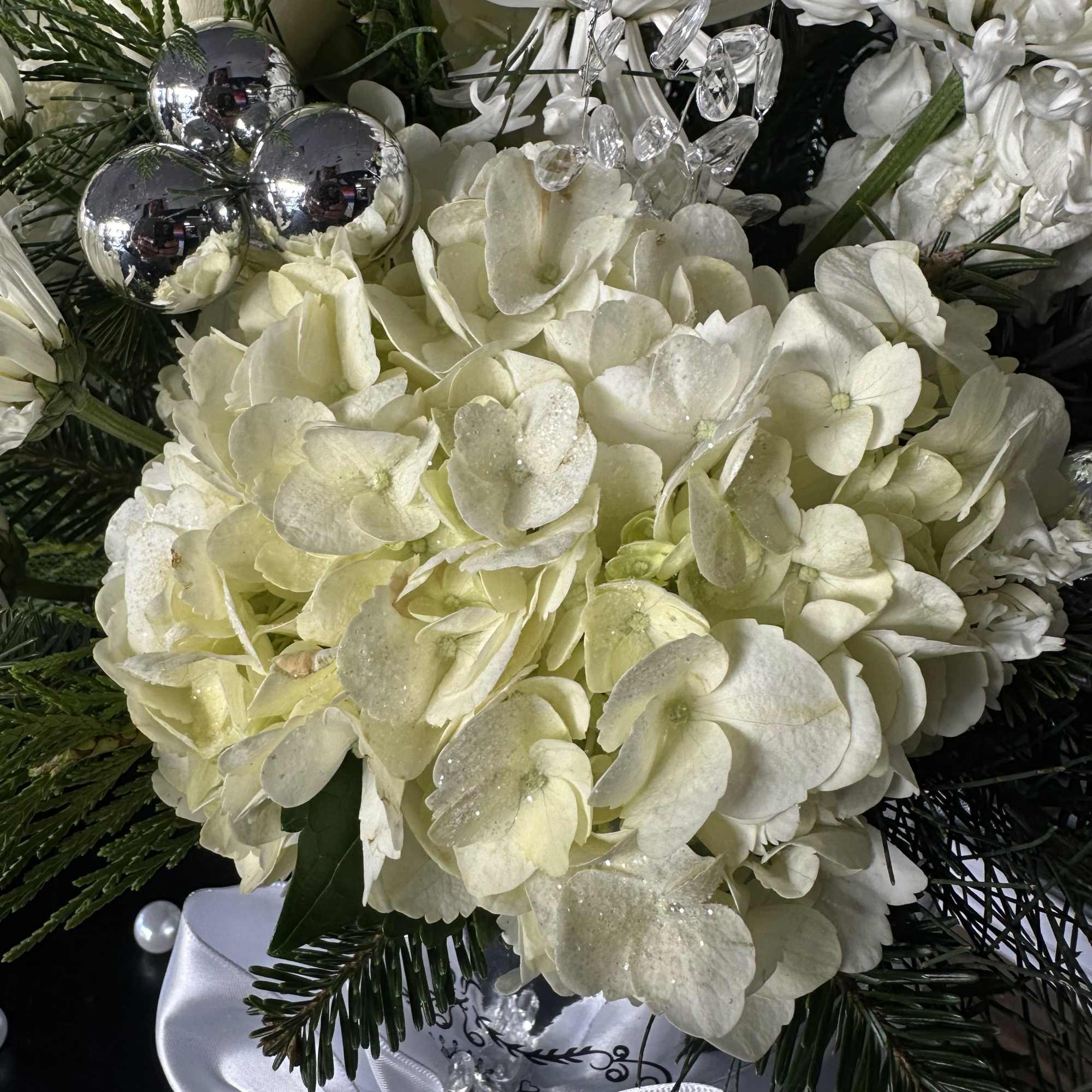 White hydrangea bouquet with silver ornaments and a white ribbon