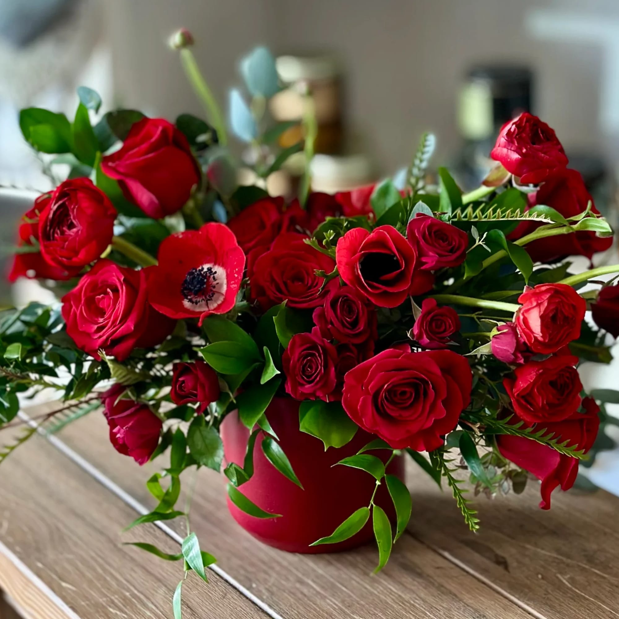 Red roses and anemone in a red vase