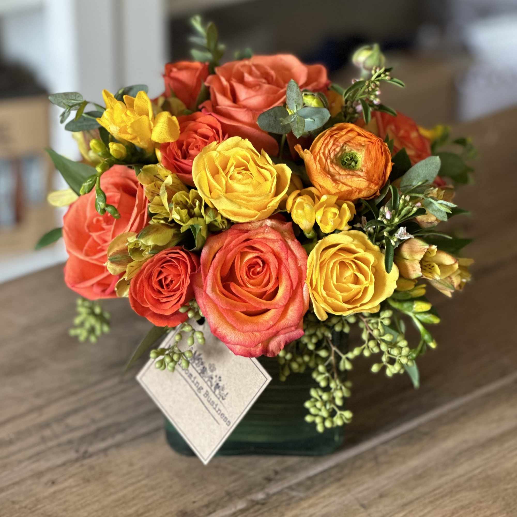 Bouquet of orange and yellow roses in a square vase
