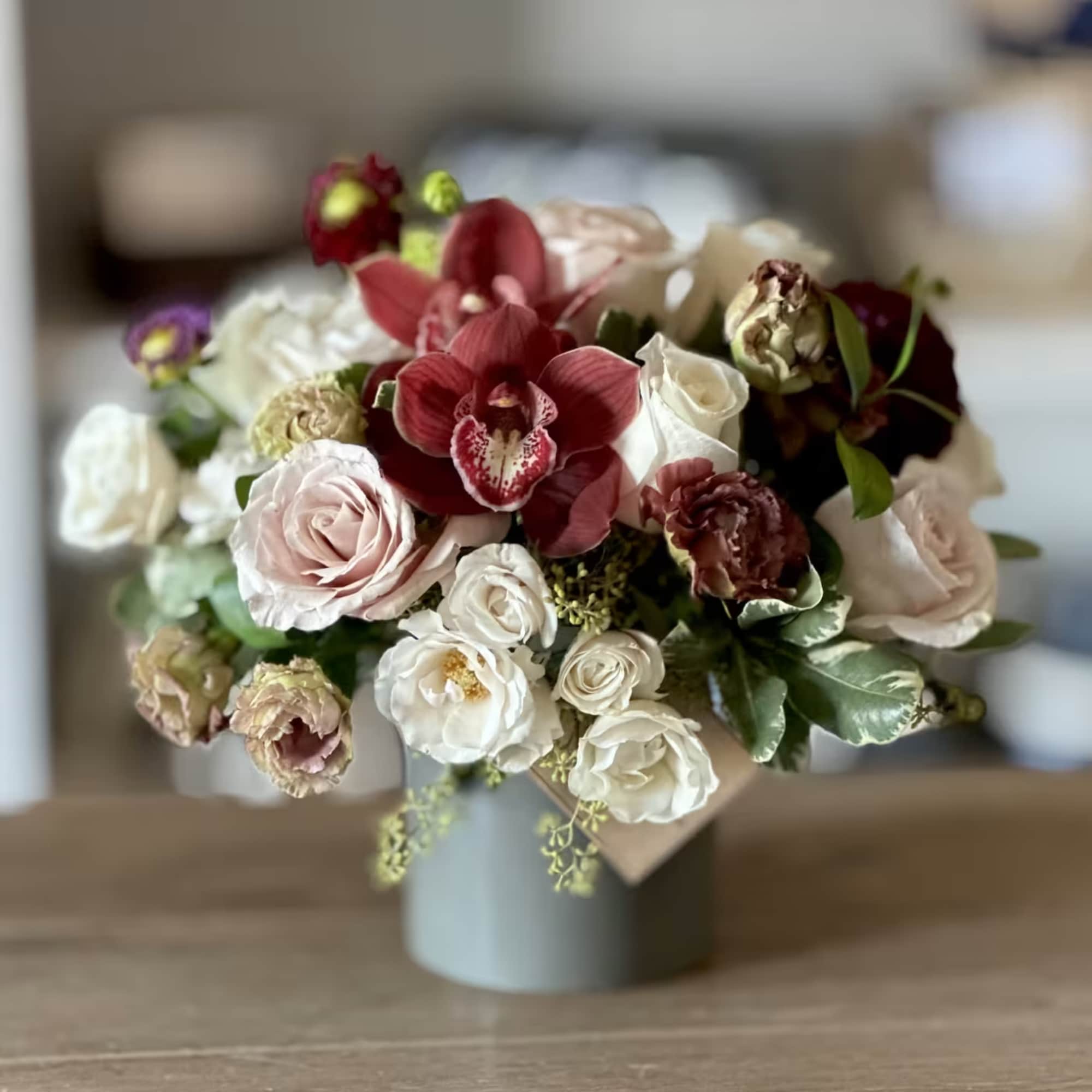 Bouquet of red orchids and pale roses in a gray vase