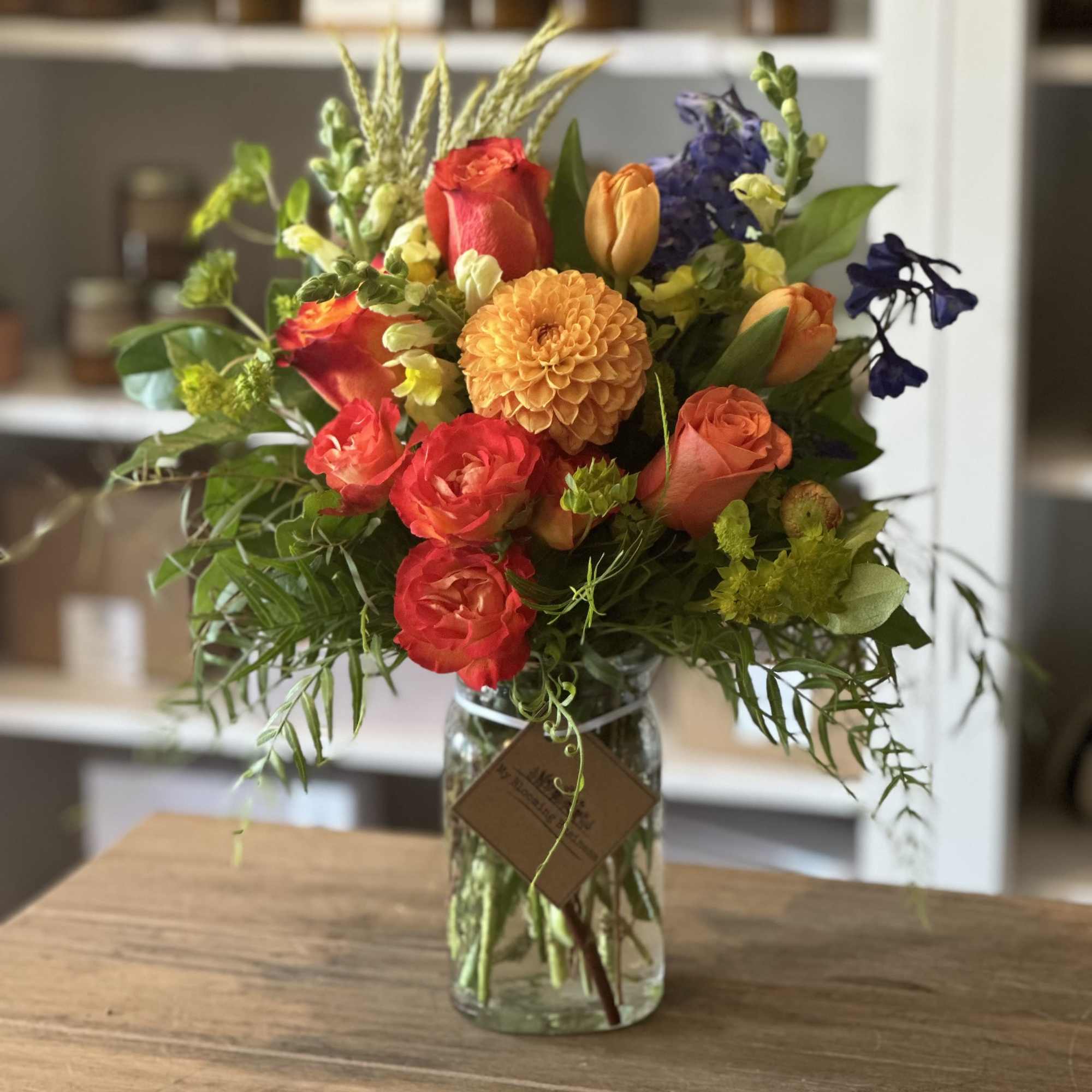 Mixed bouquet of orange, red, and purple flowers in a glass vase