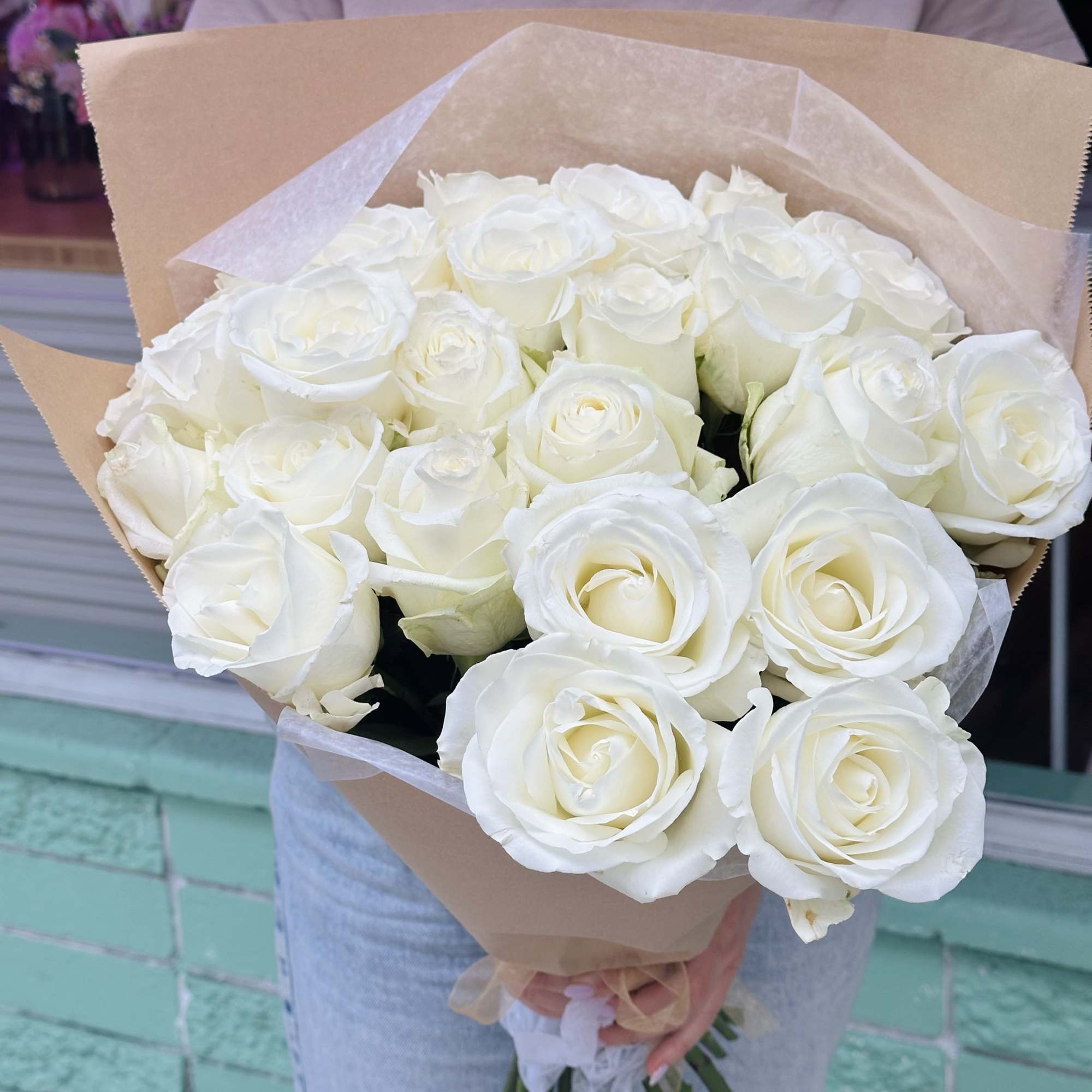 Hand-tied bouquet of large white roses wrapped in brown paper