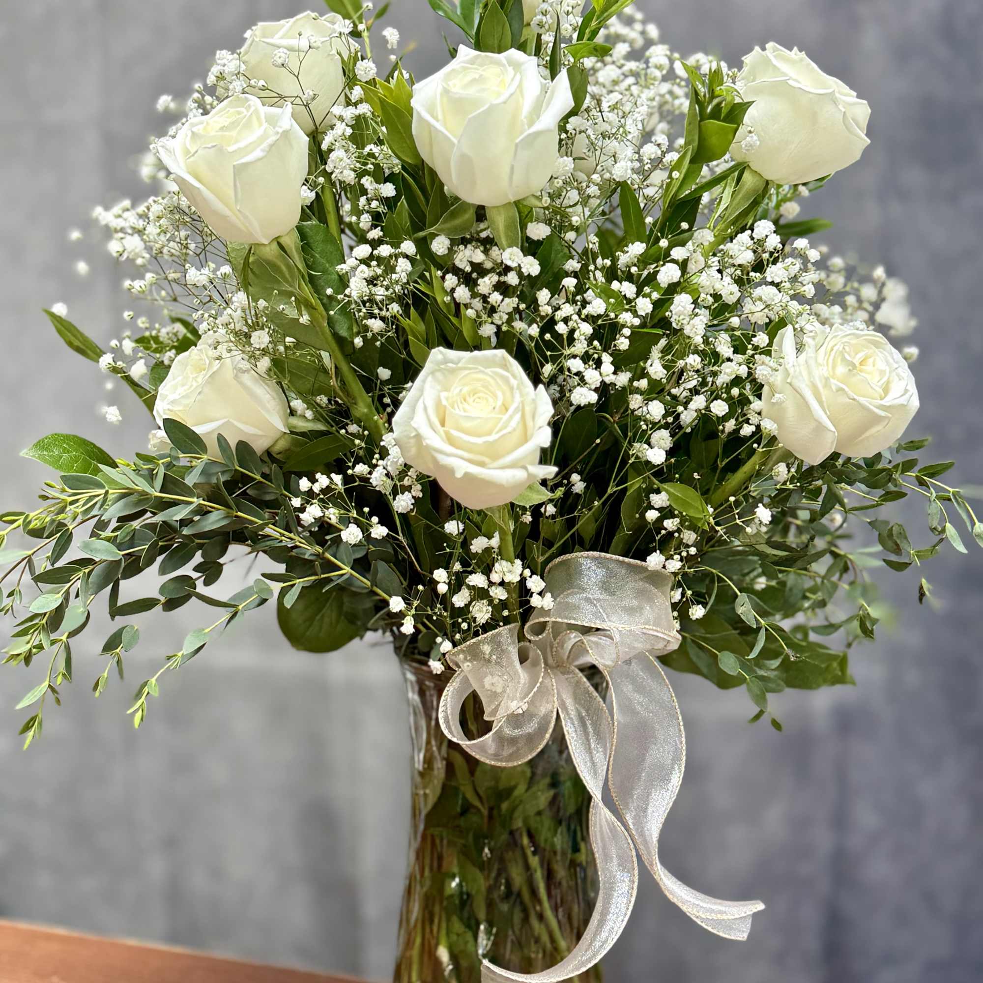 Classic White Roses 
A Timeless arrangement of white roses, accented with baby&rsquo;s