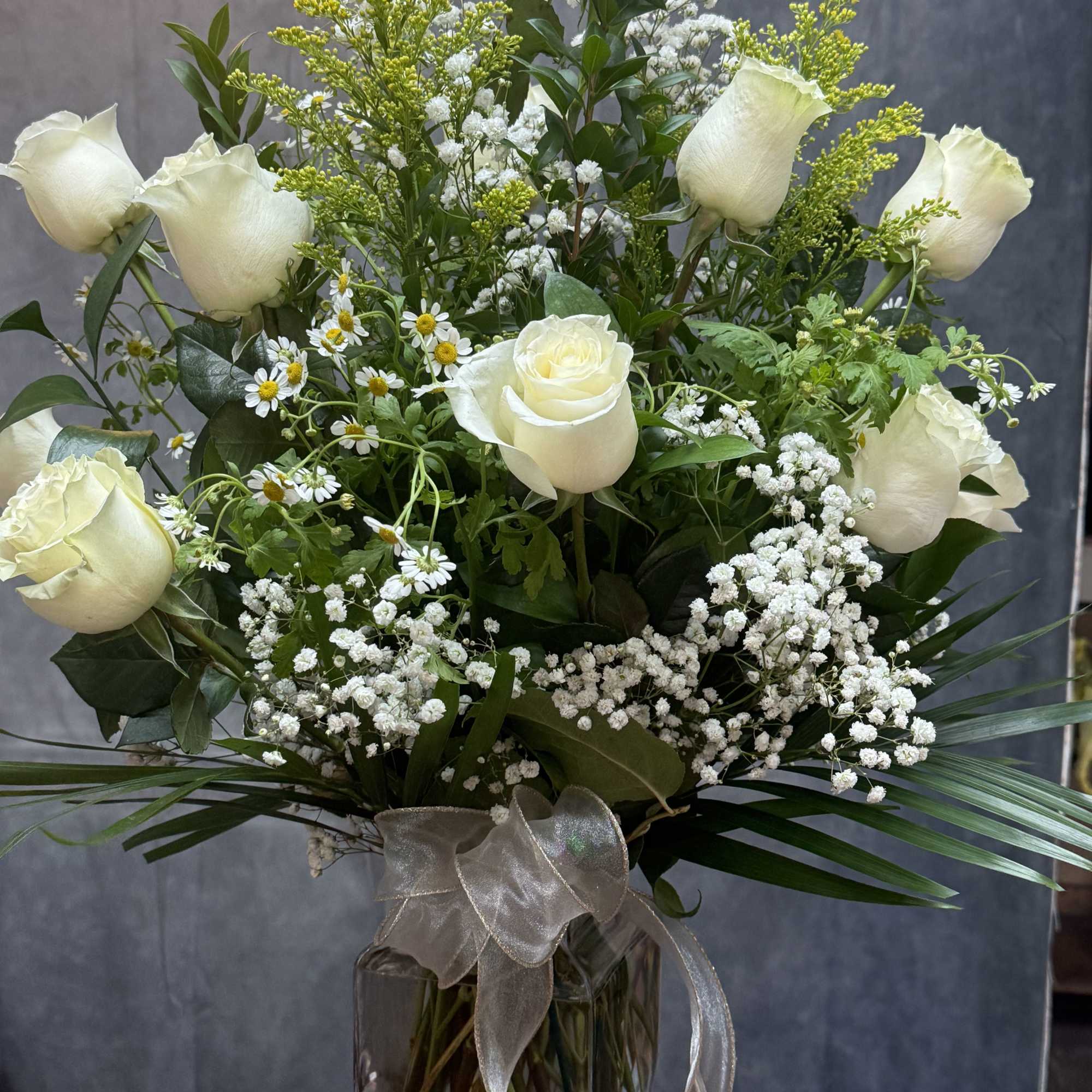 Classic White Roses 
A Timeless arrangement of white roses, accented with baby&rsquo;s