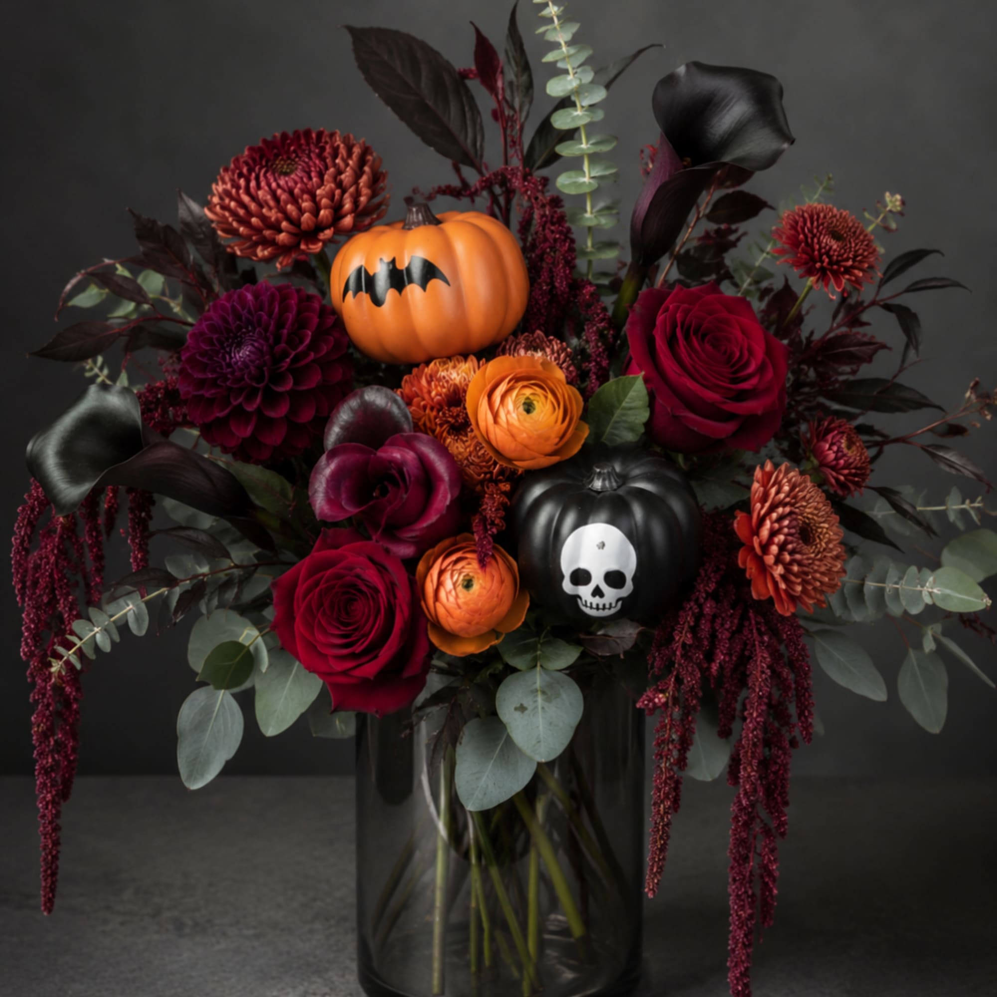Halloween bouquet with roses, dahlias, and pumpkin decorations in a dark vase