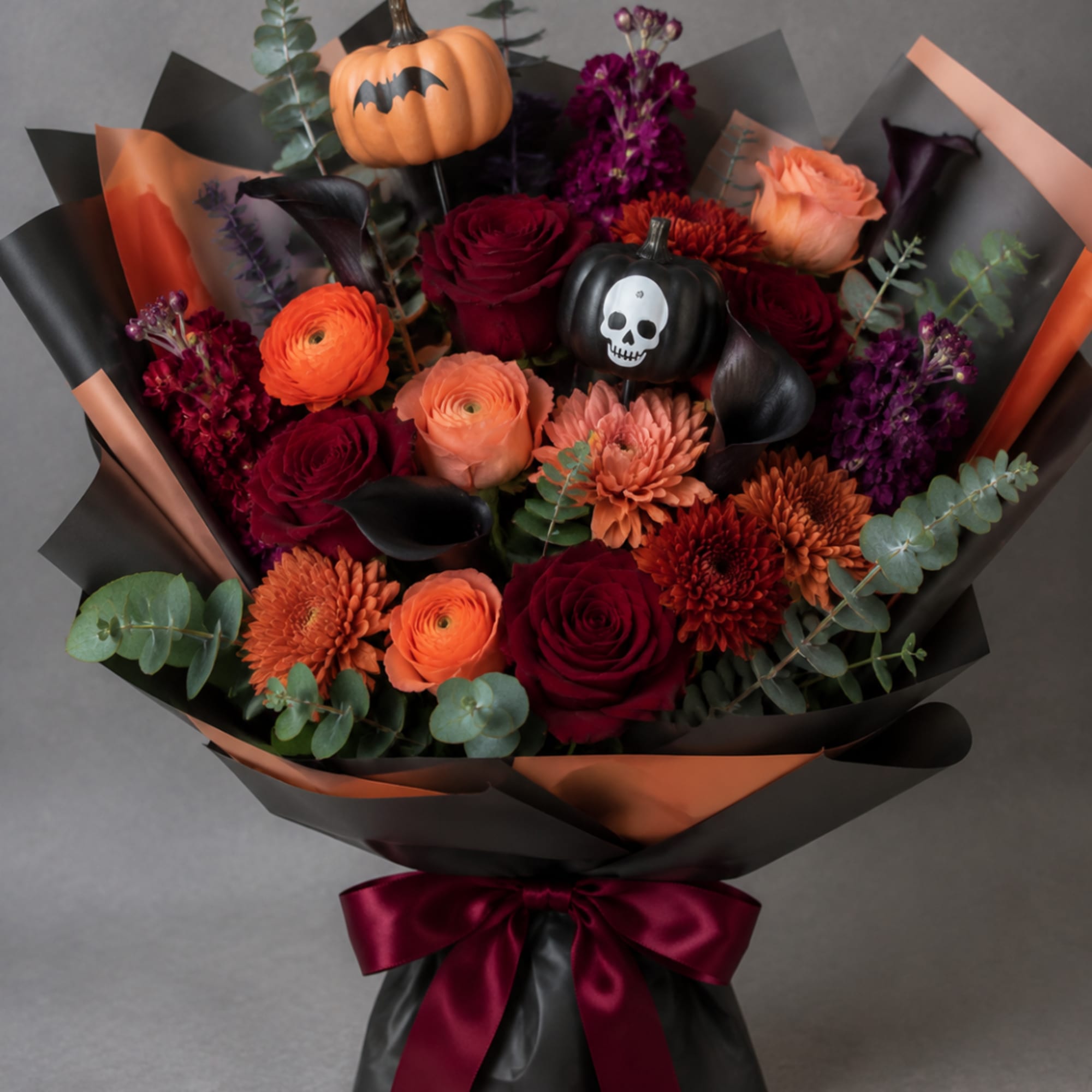 Bouquet of orange, burgundy, and purple flowers with Halloween pumpkin picks