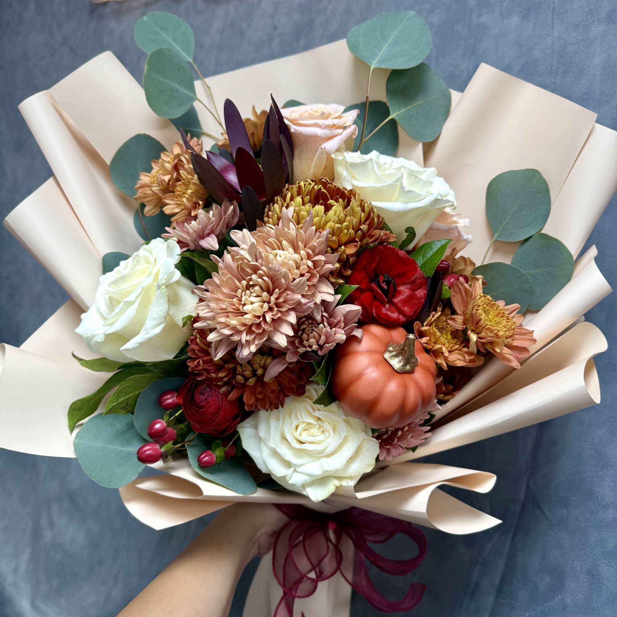 Hand-tied bouquet of roses and chrysanthemums with a small pumpkin accent