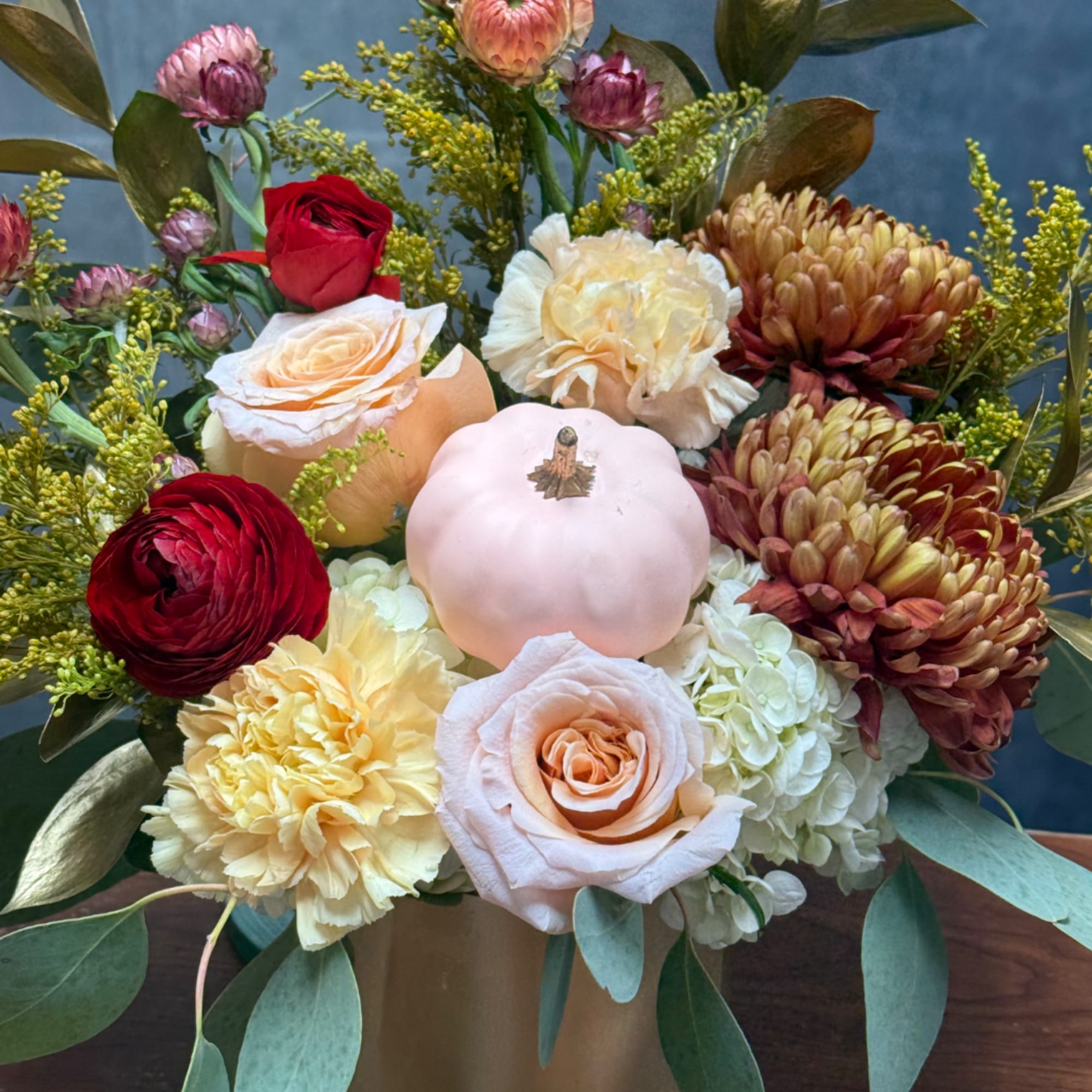 Mixed bouquet with roses, chrysanthemums, hydrangea, and a small pumpkin in a vase