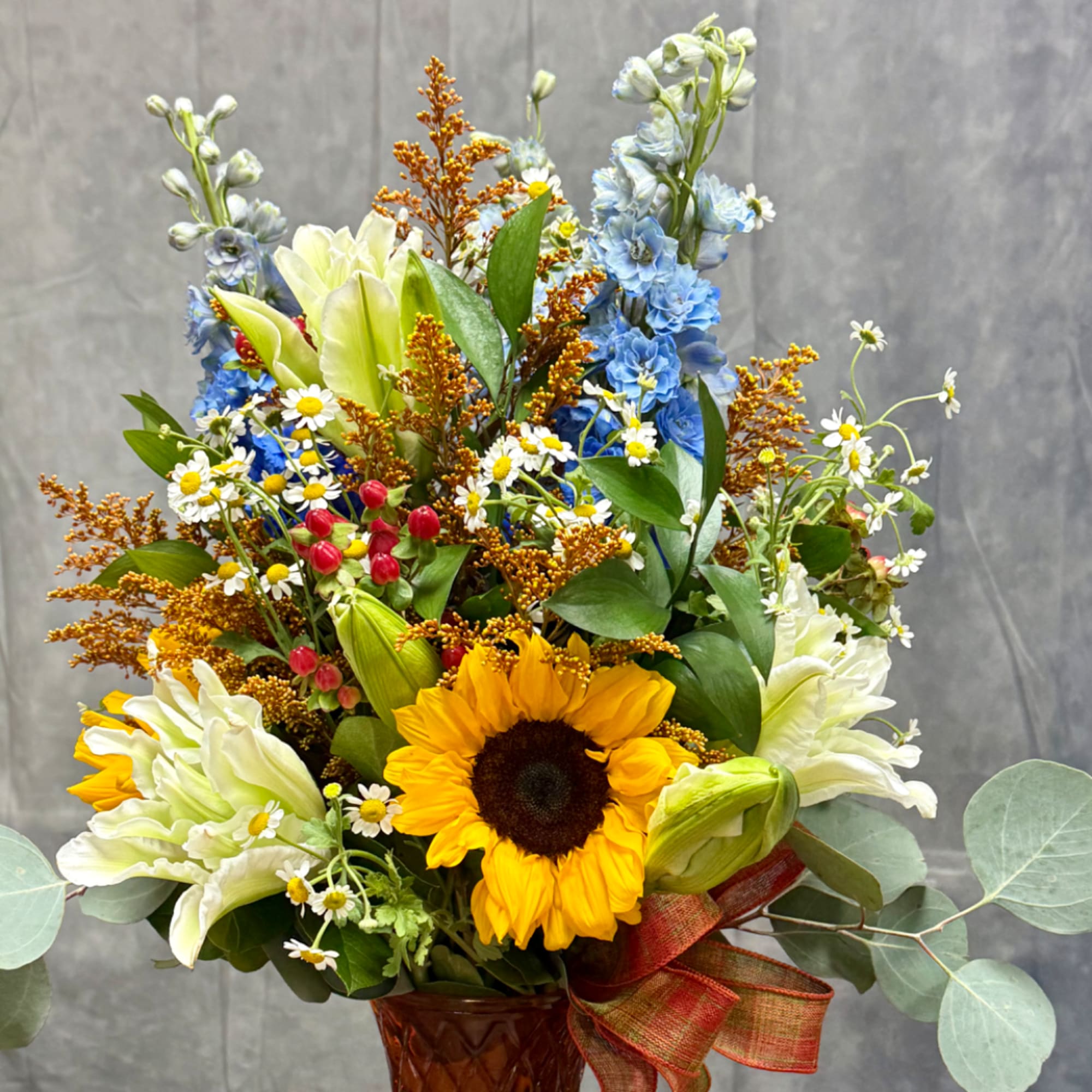 Mixed bouquet with sunflowers, blue flowers, and white blooms in a vase