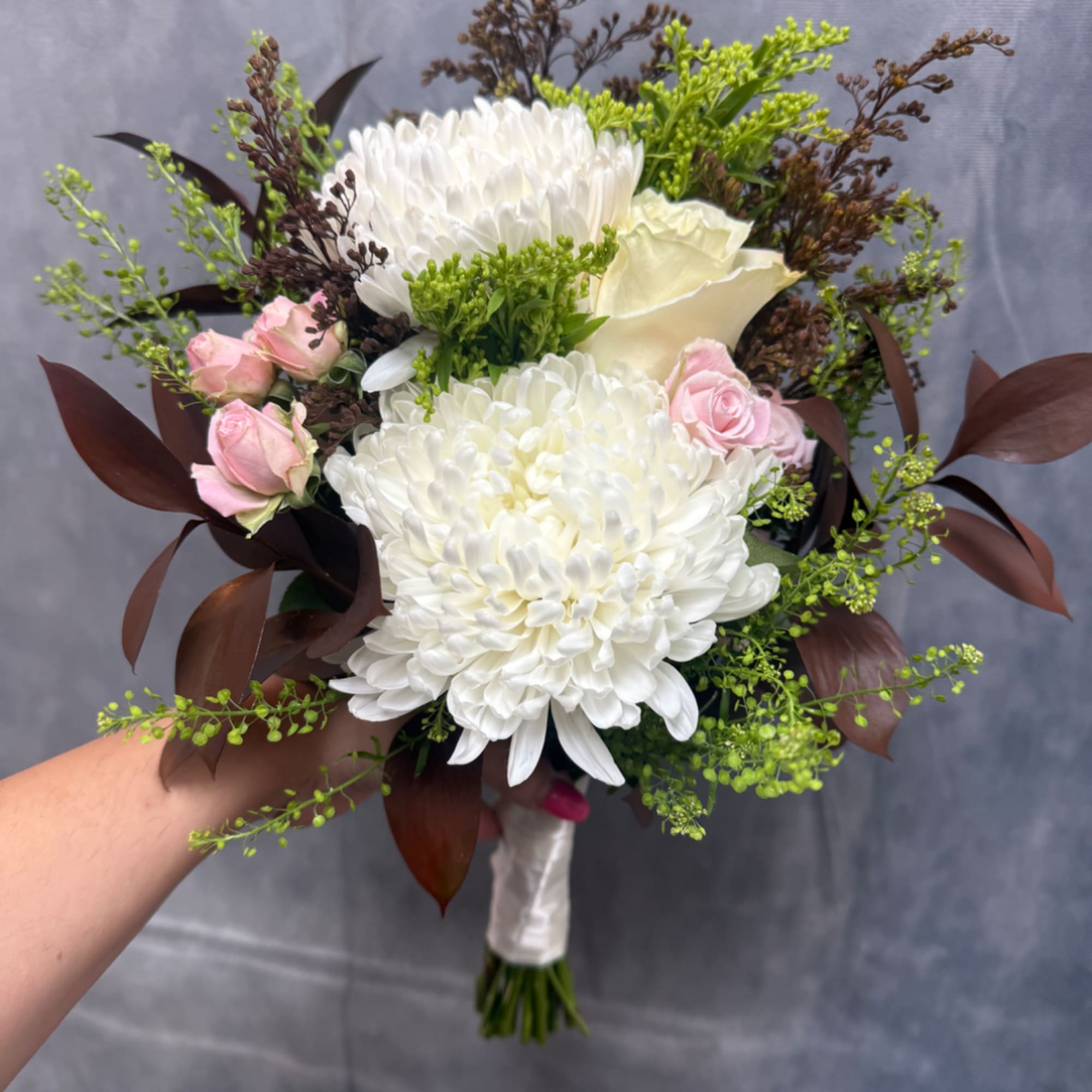 Handheld bouquet of white chrysanthemums, pink roses, and cream calla lilies
