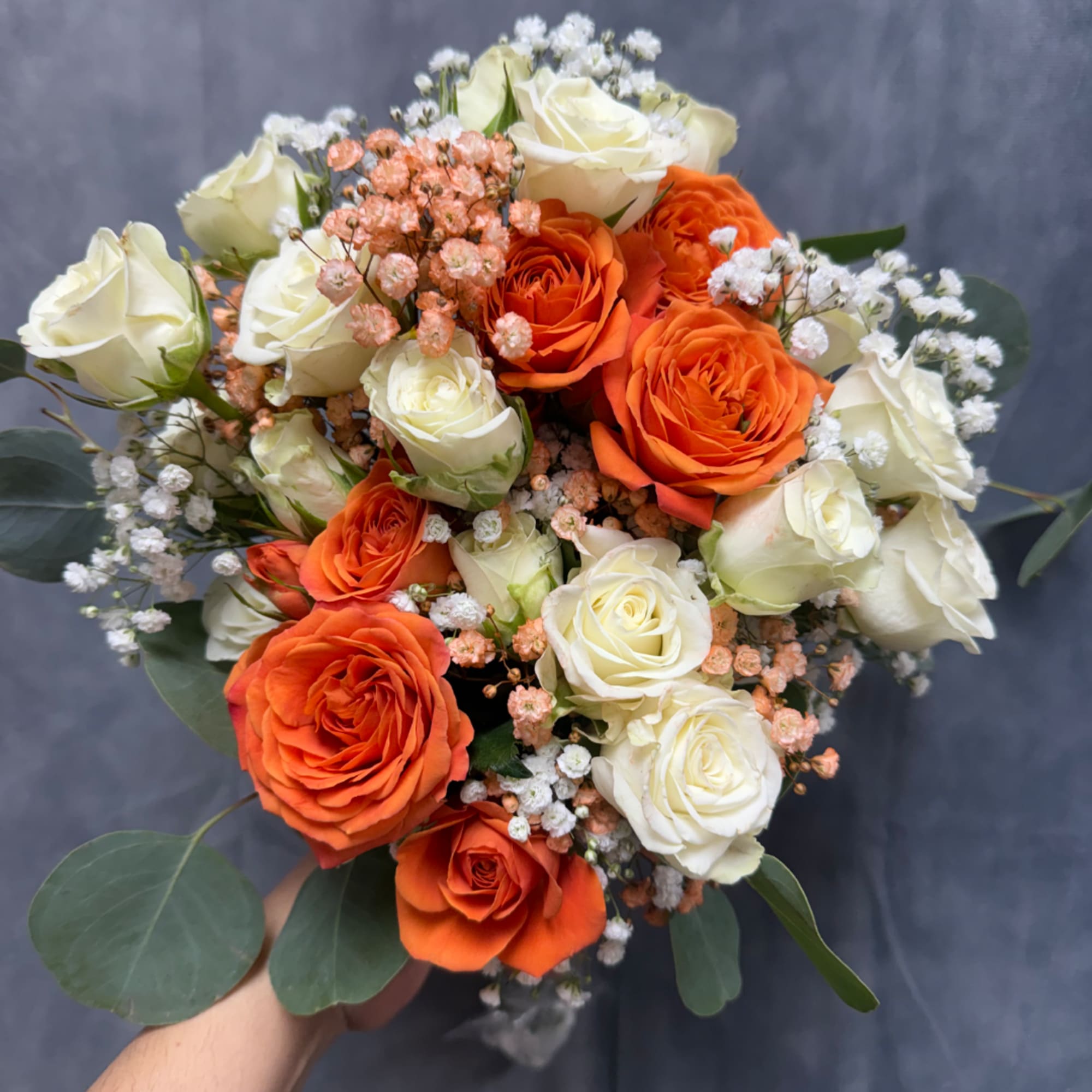 Bouquet of orange and white roses with small filler flowers