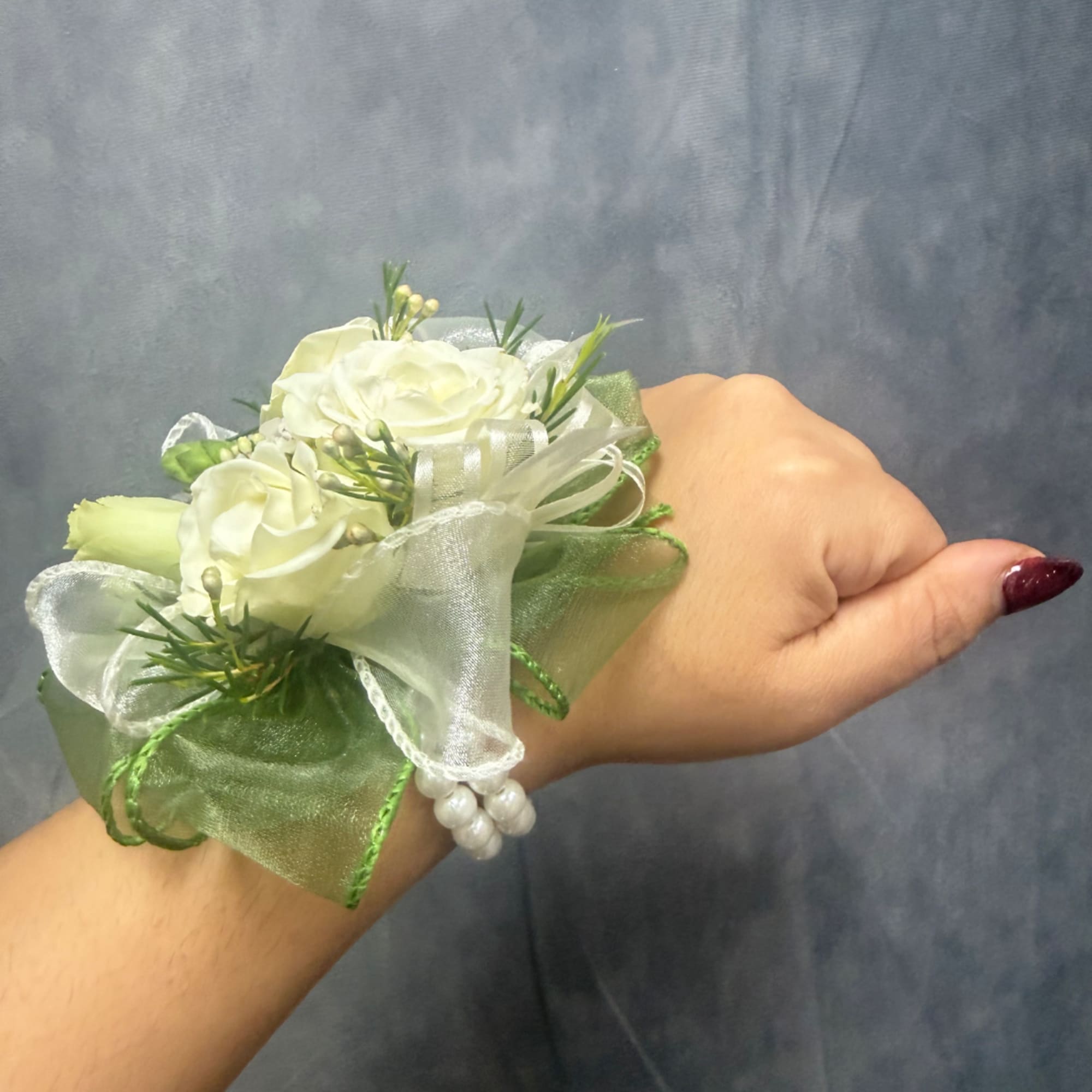 White floral wrist corsage with ribbon on a person's wrist