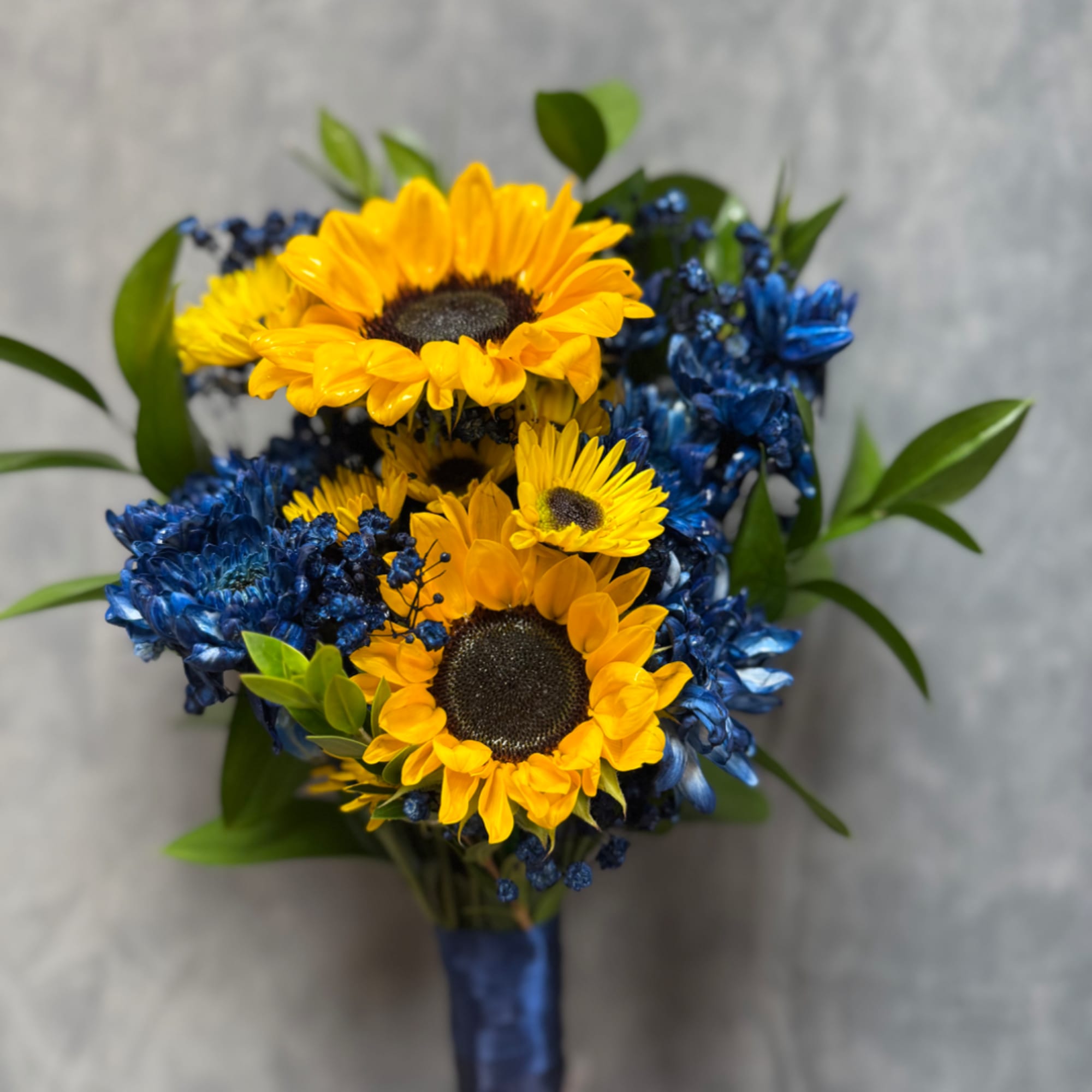 Bouquet of yellow sunflowers and blue flowers with green leaves