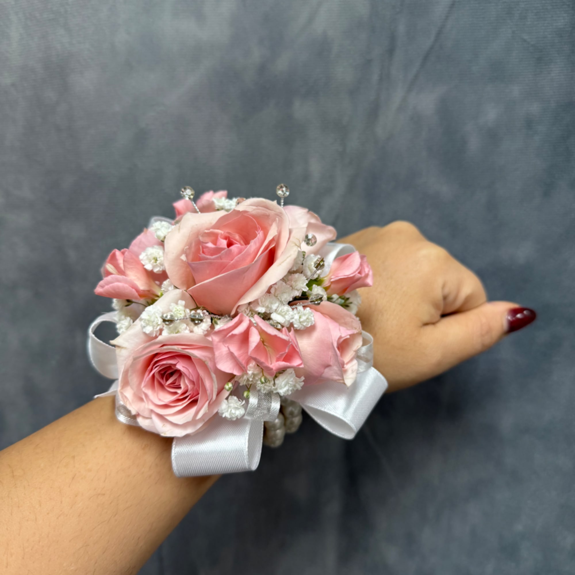 Pink rose wrist corsage with white ribbon and small white filler flowers