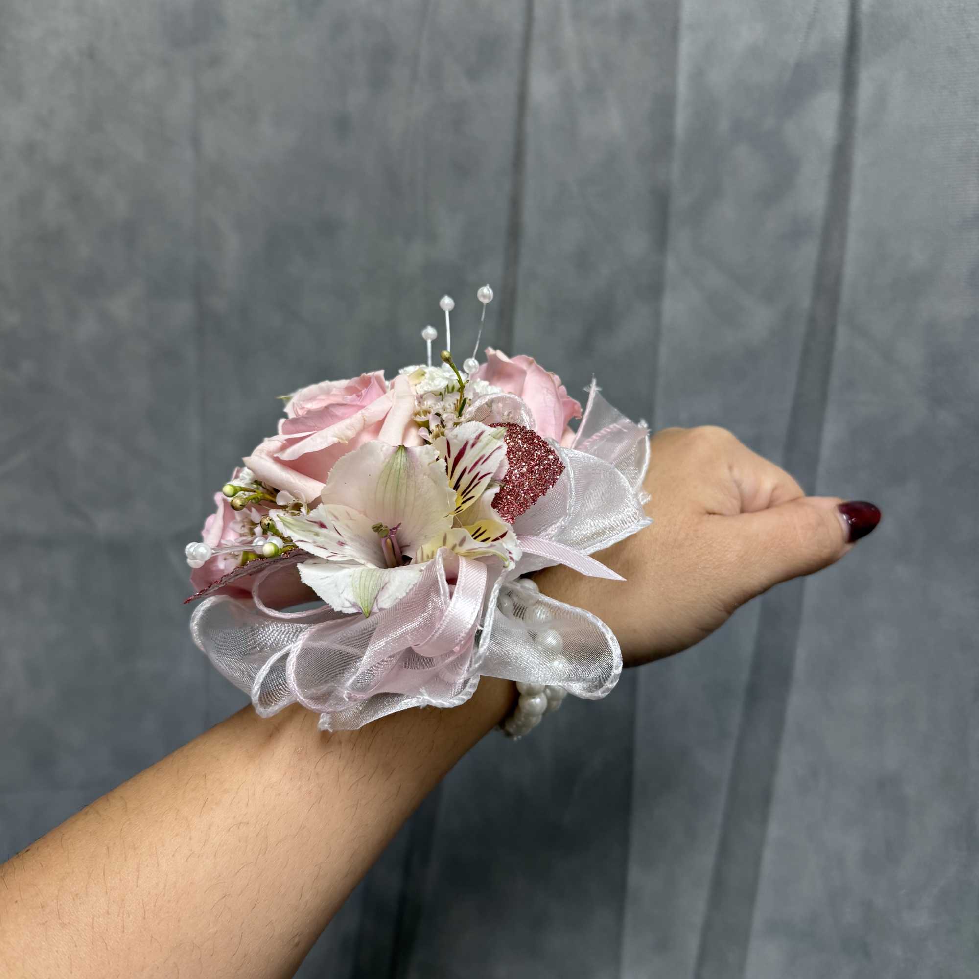 Pink rose wrist corsage with white ribbon and small accent flowers