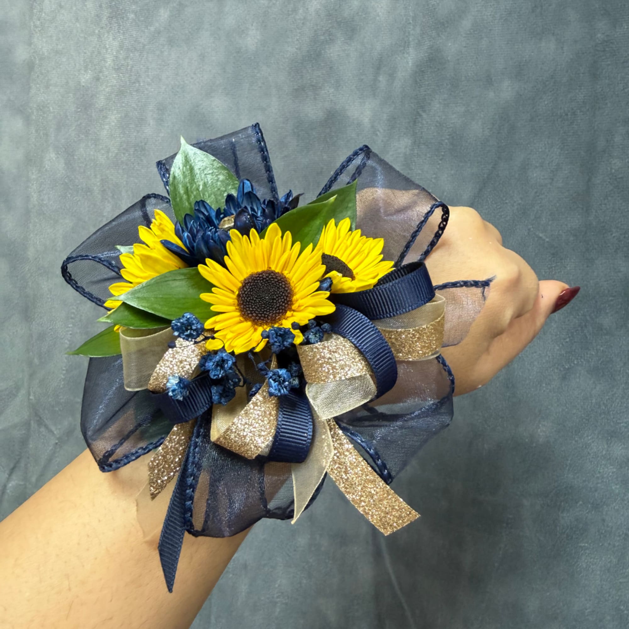 Yellow daisy wrist corsage with navy ribbon and gold accents