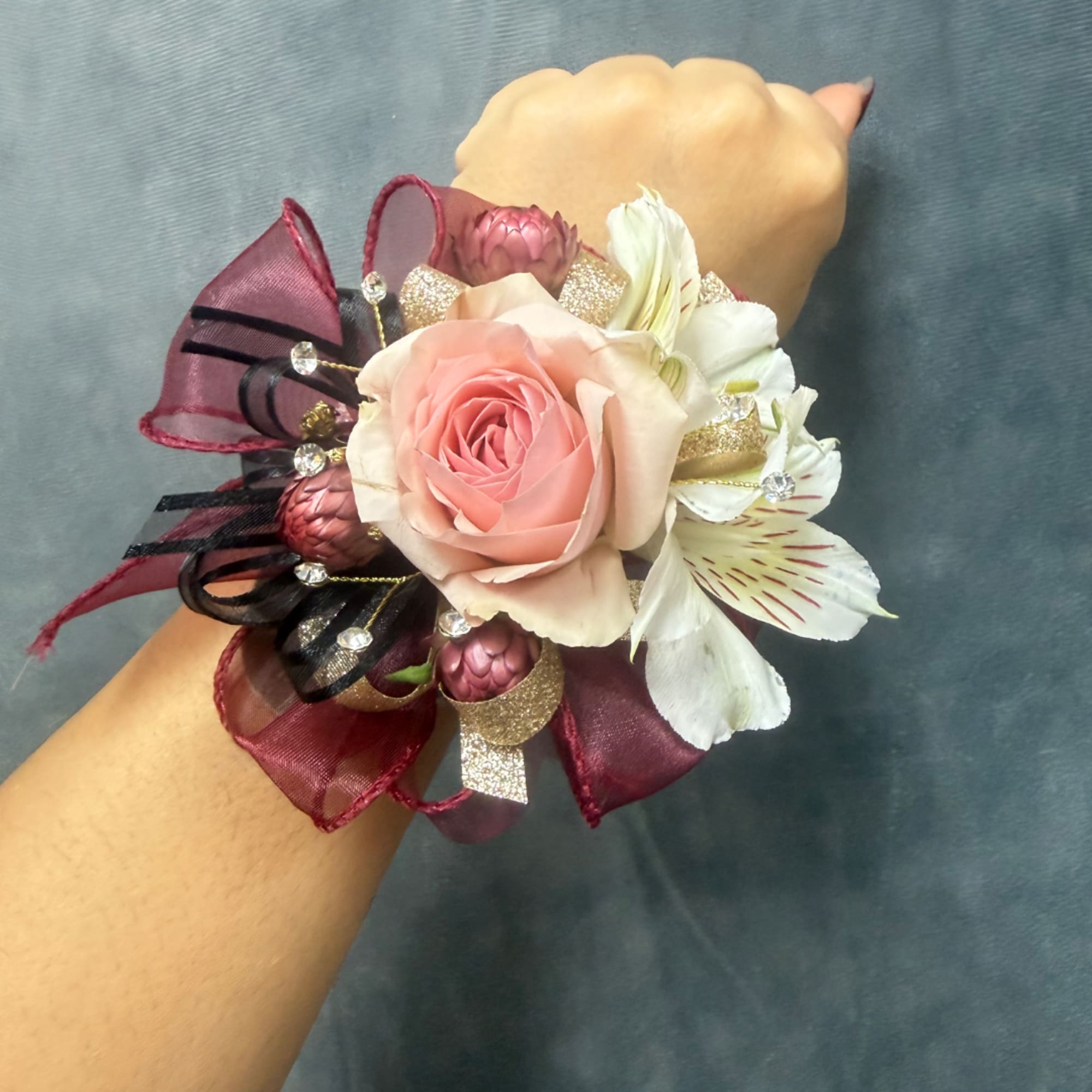 Pink rose wrist corsage with white flowers and burgundy ribbon