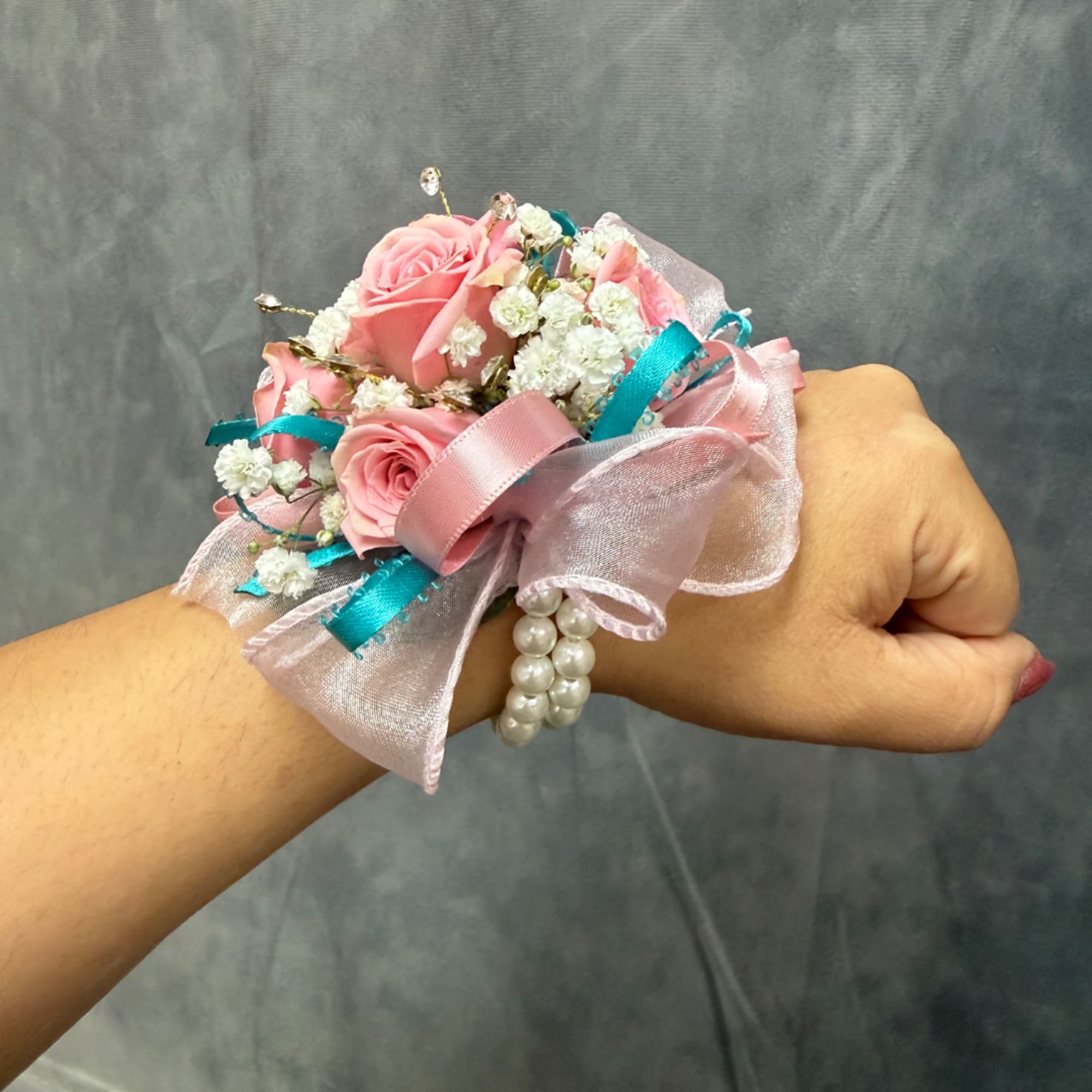 Pink rose wrist corsage with white filler flowers and ribbon on a wrist, photo 2 of 2