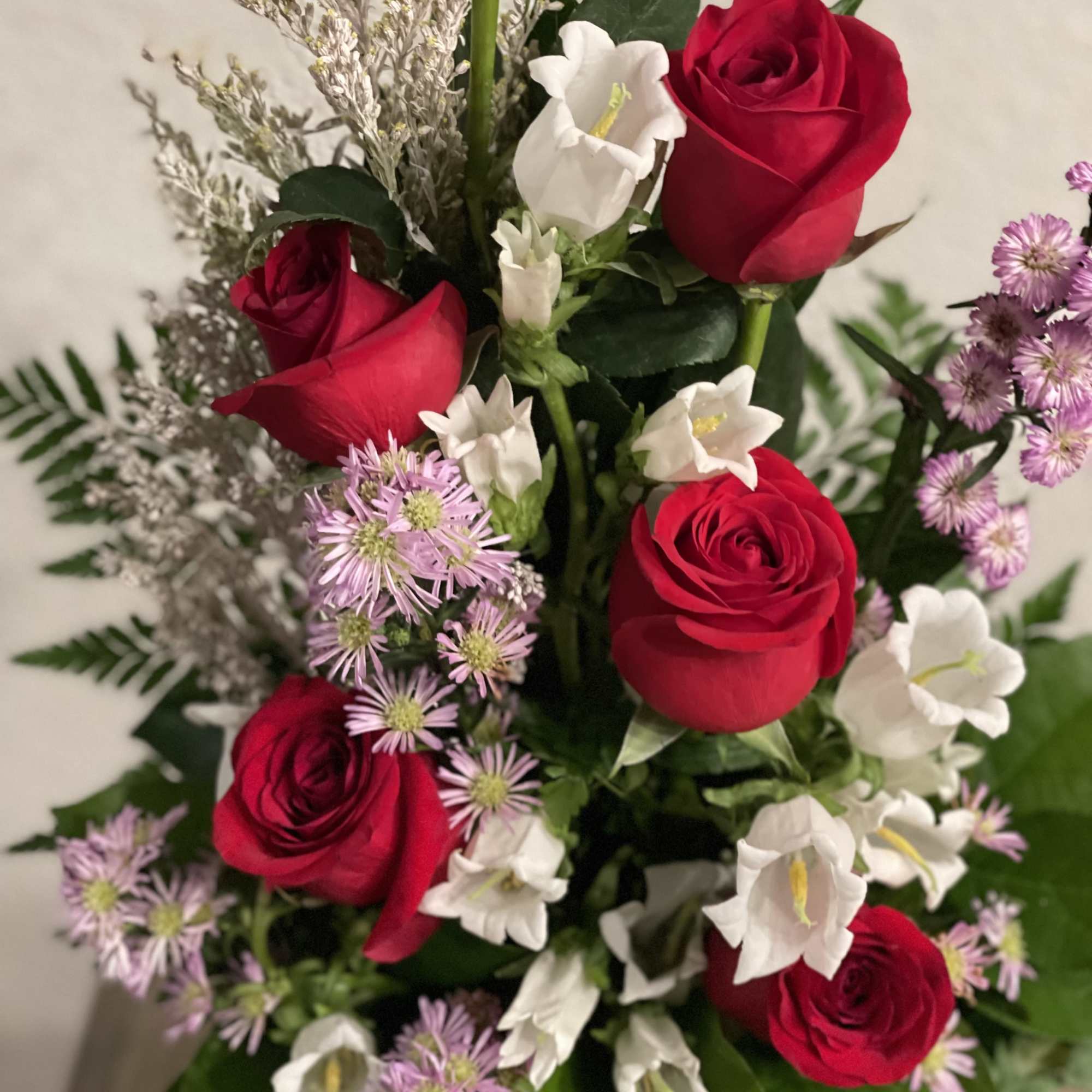 Bouquet of red roses, white bellflowers, and small lavender flowers