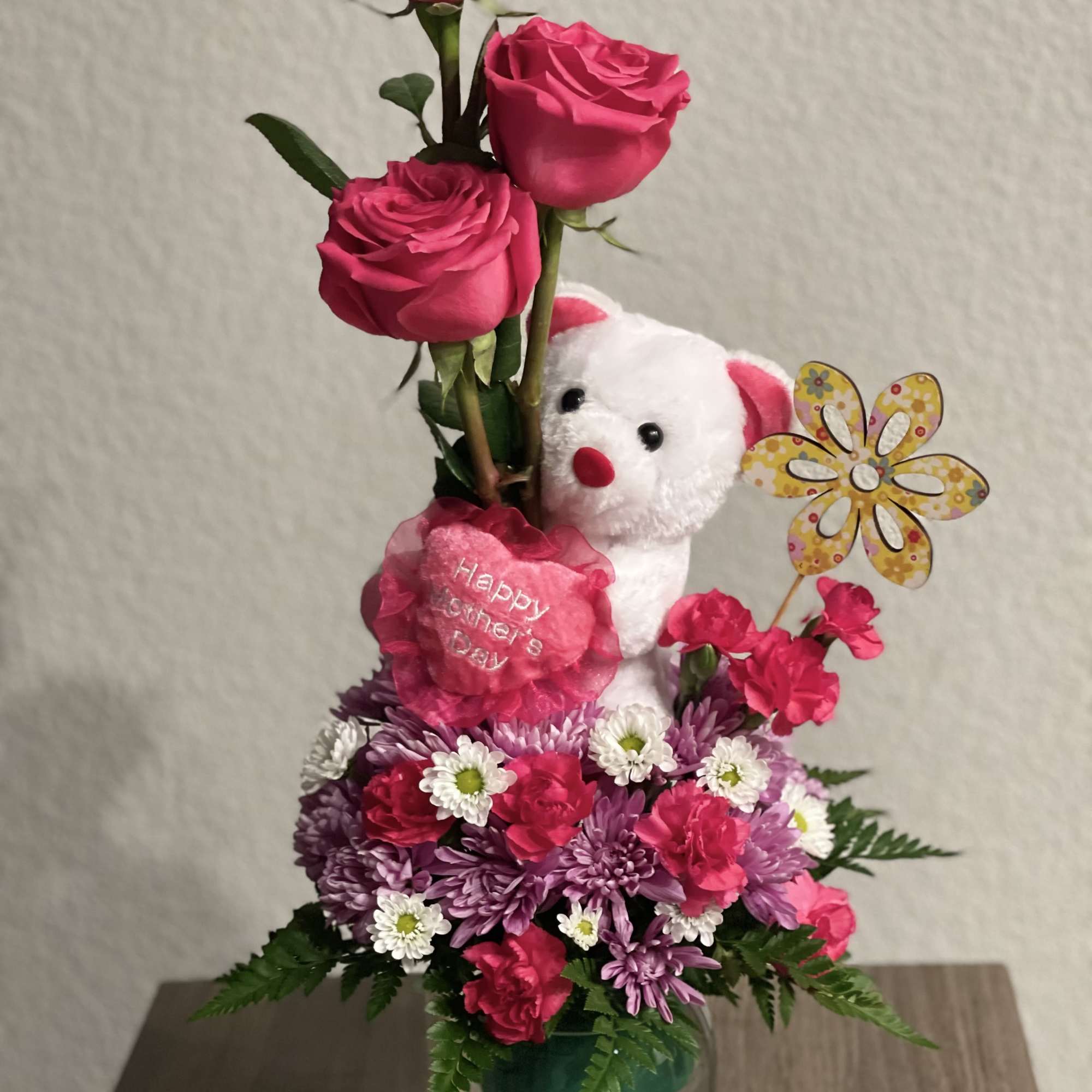 Pink rose arrangement with a teddy bear and flowers in a glass vase