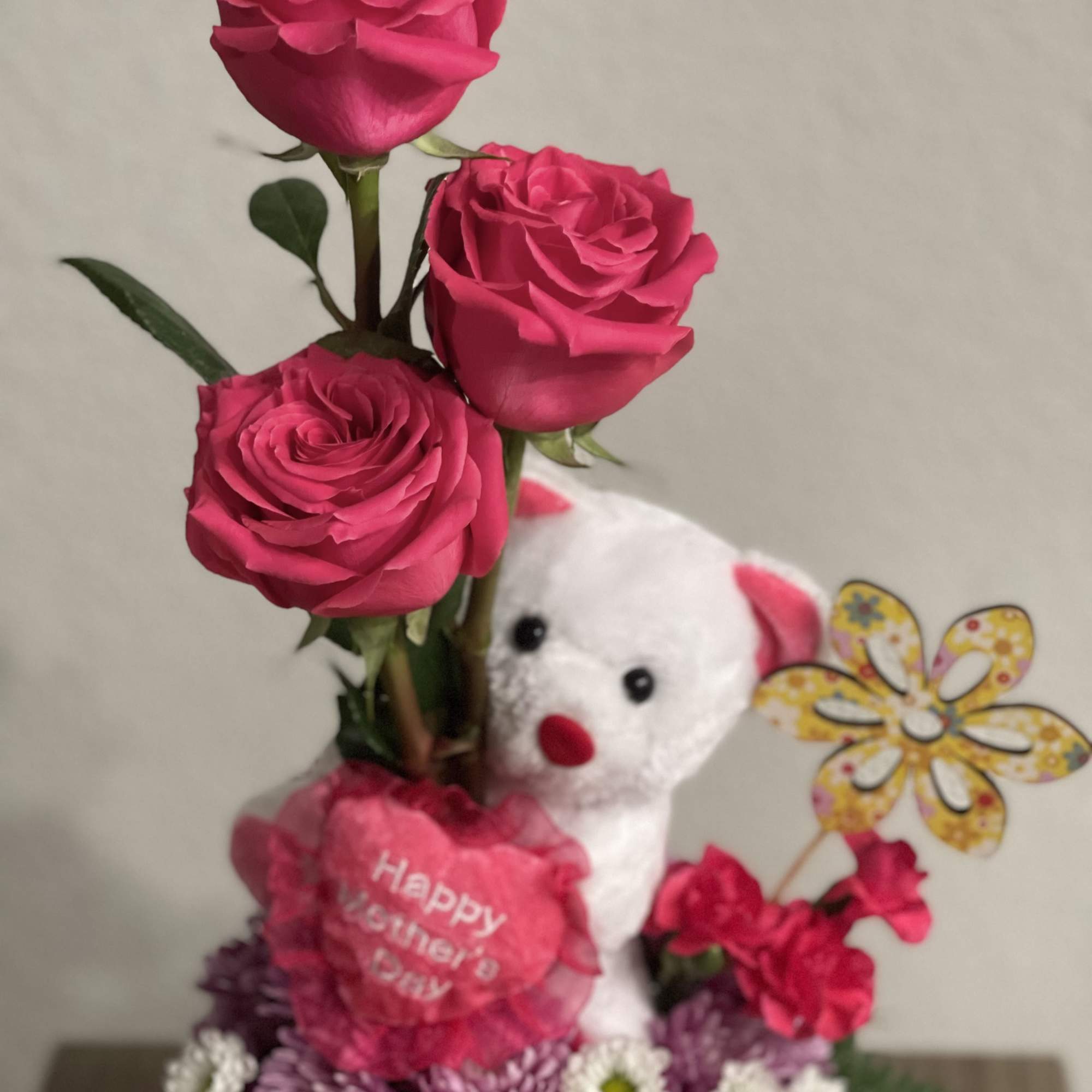 Pink roses arranged with a teddy bear and a "Happy Mother's Day" sign