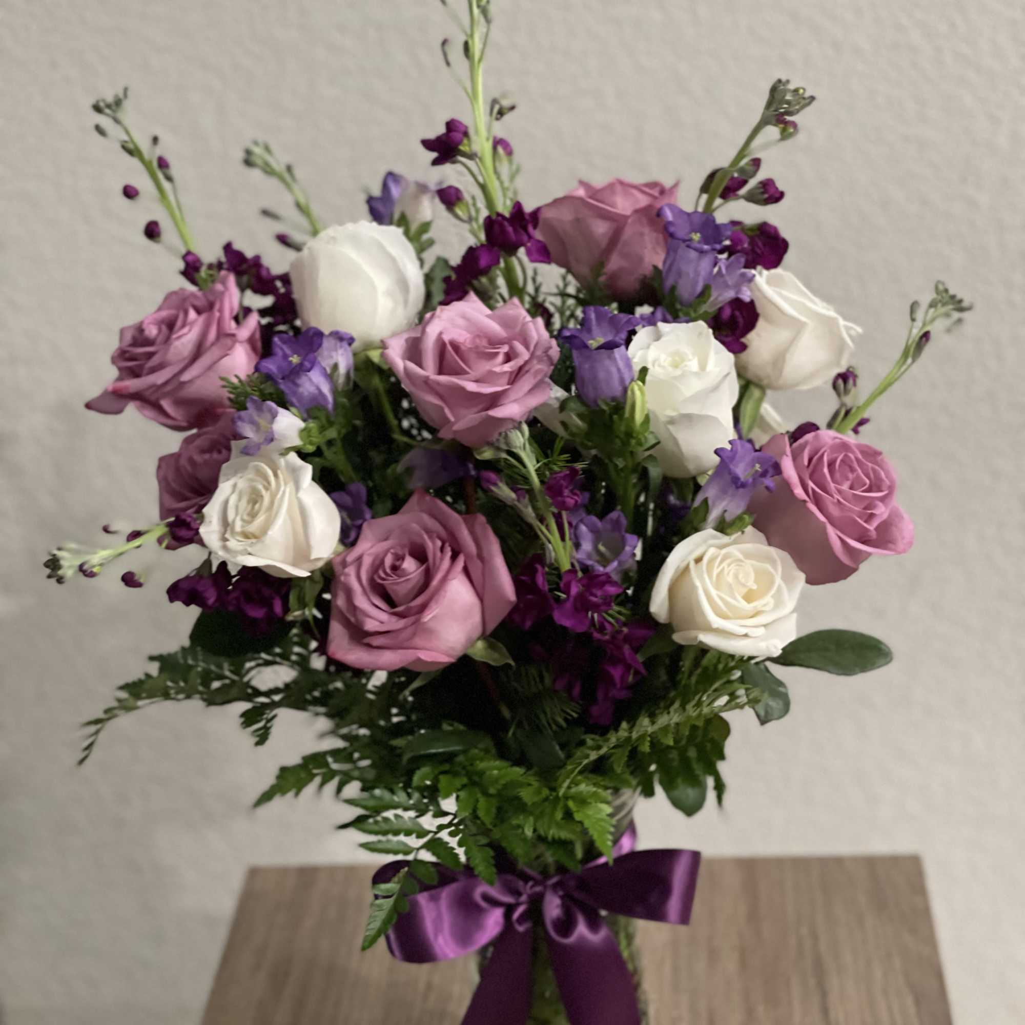 Pink and white roses with purple flowers in a glass vase