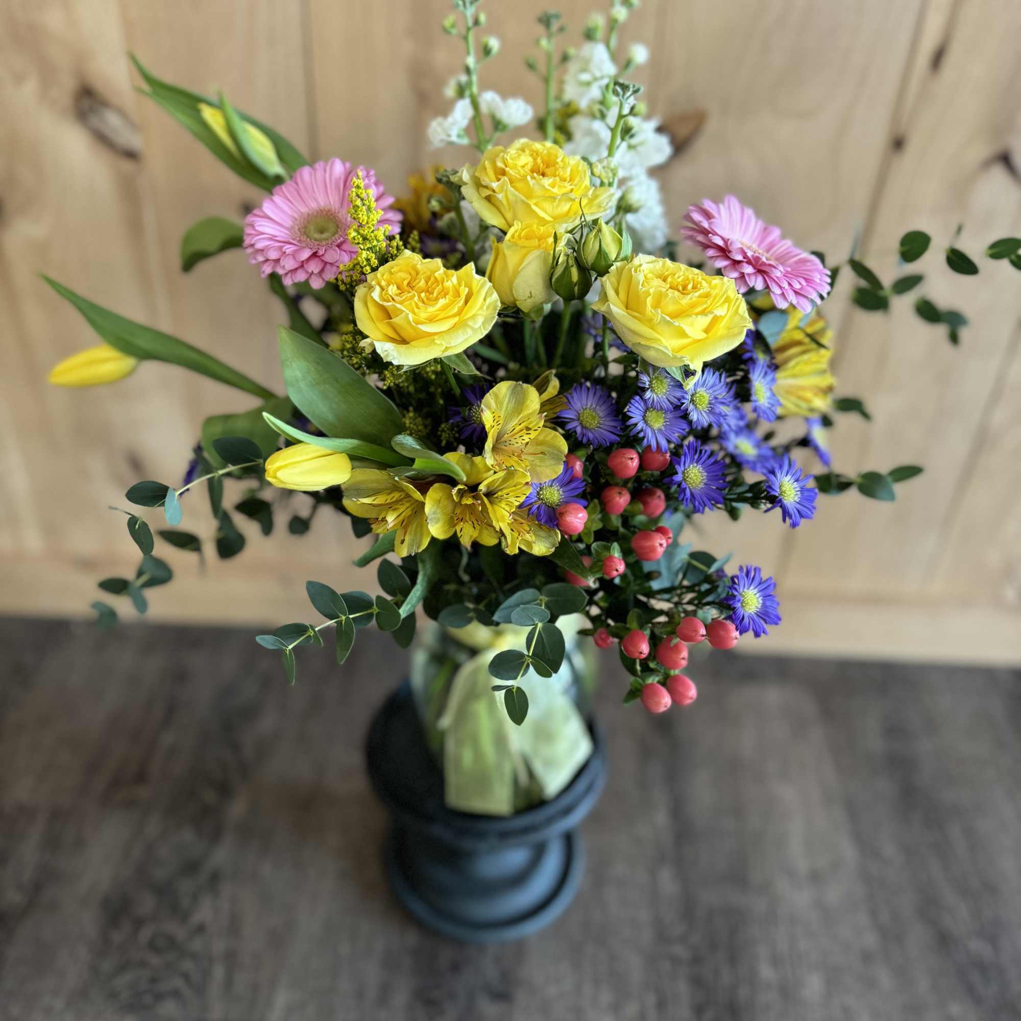 Mixed bouquet with yellow roses, pink gerbera daisies, and purple flowers in a vase