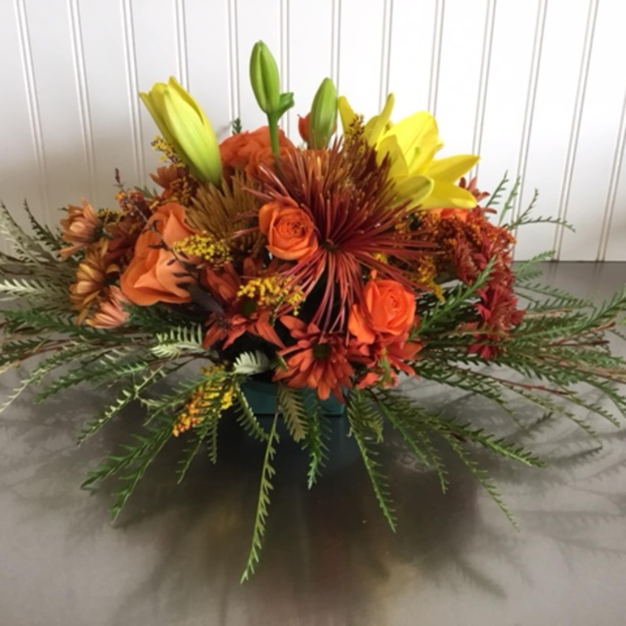 Orange and yellow floral arrangement in a low container