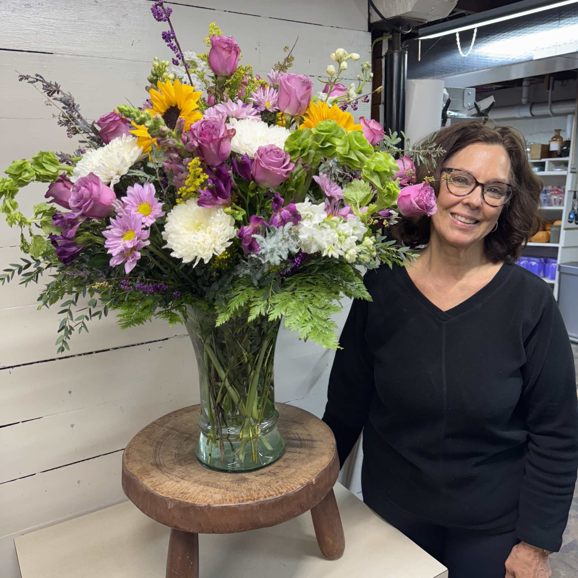 Large mixed bouquet in a glass vase with pink, white, yellow, and purple flowers