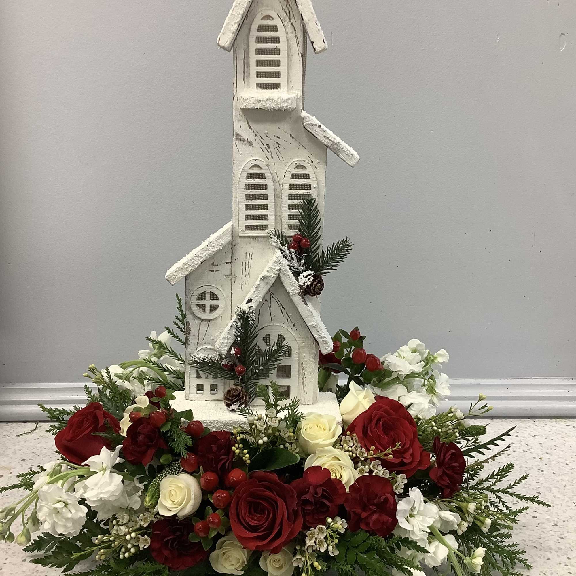 Red and white floral arrangement around a white decorative church