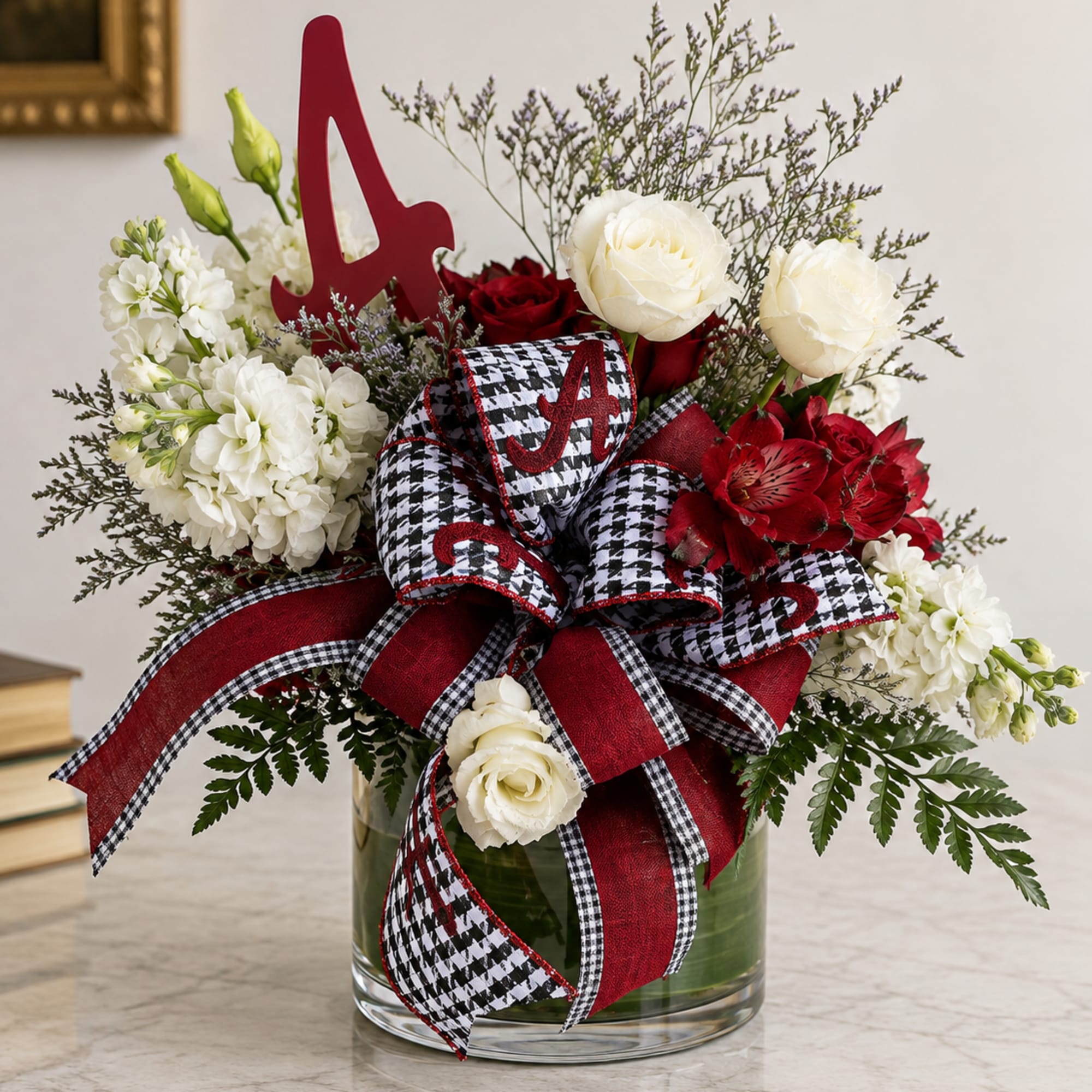 Red and white floral arrangement in a glass vase with a large ribbon bow
