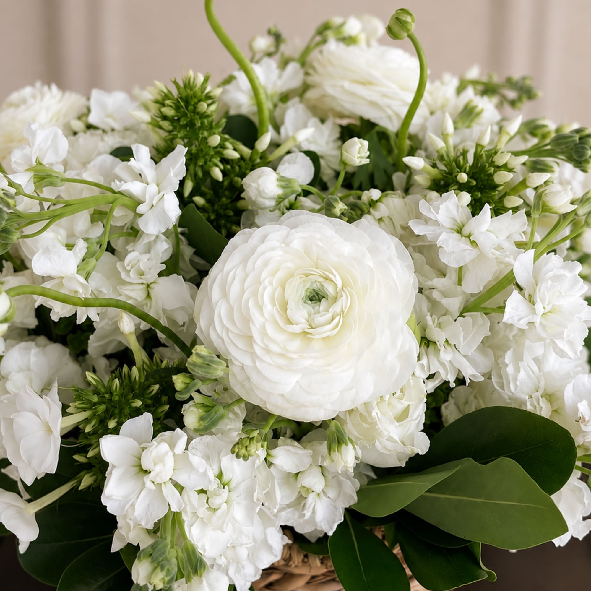 White flowers arranged in a woven basket with green accents