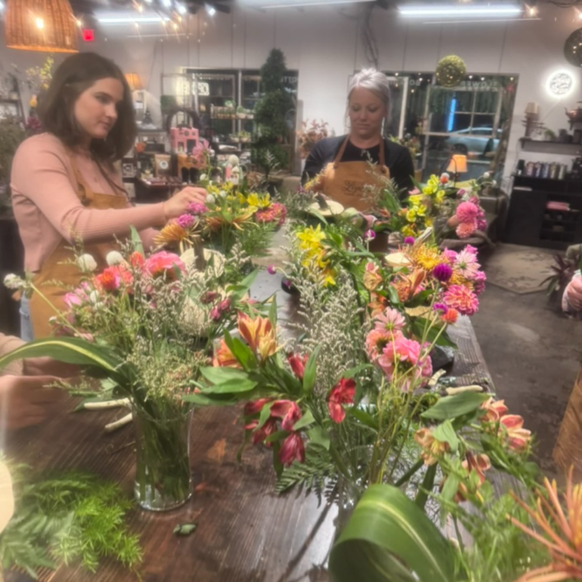 Florists arranging colorful mixed bouquets on a worktable in a shop