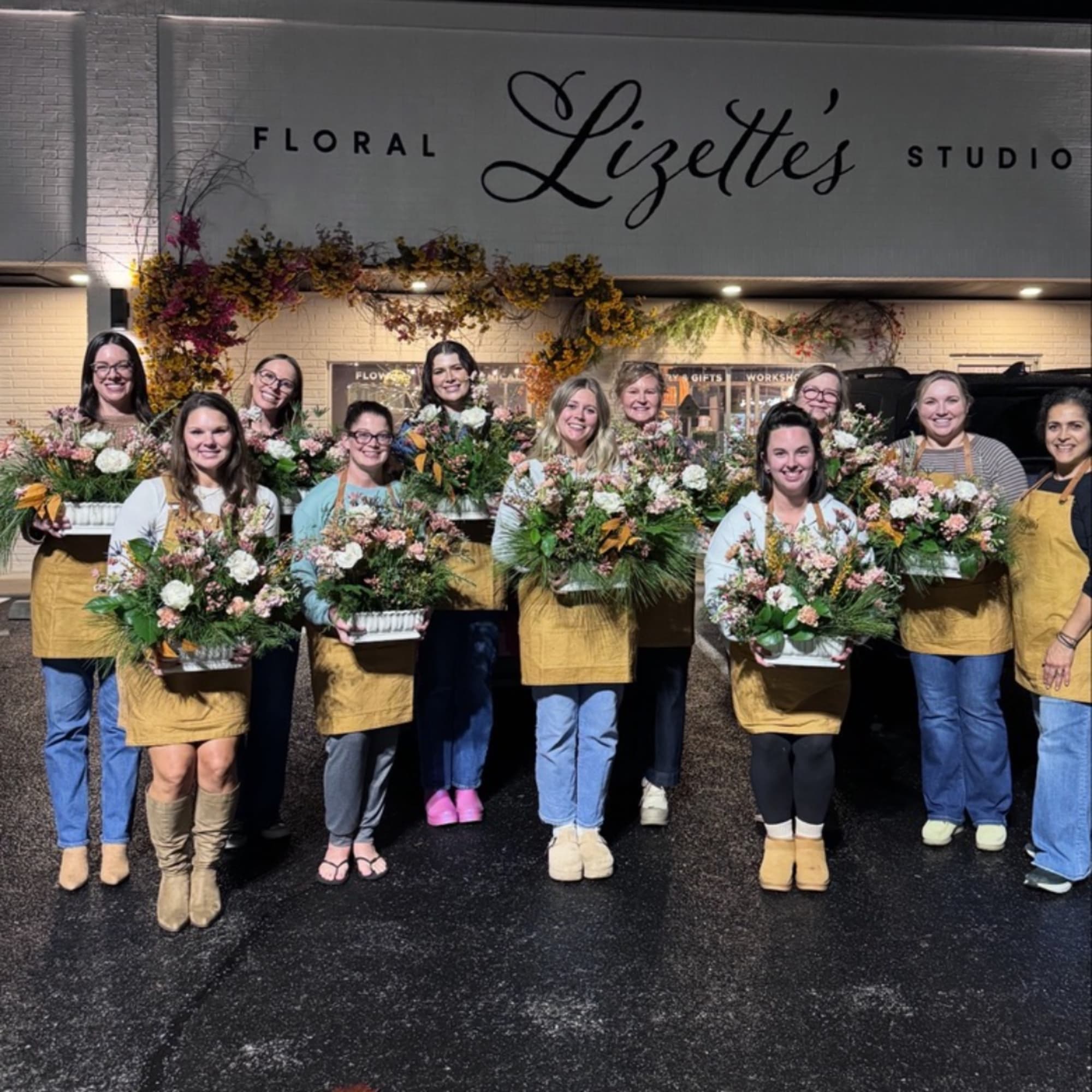 Group of florists holding mixed flower arrangements outside a floral studio
