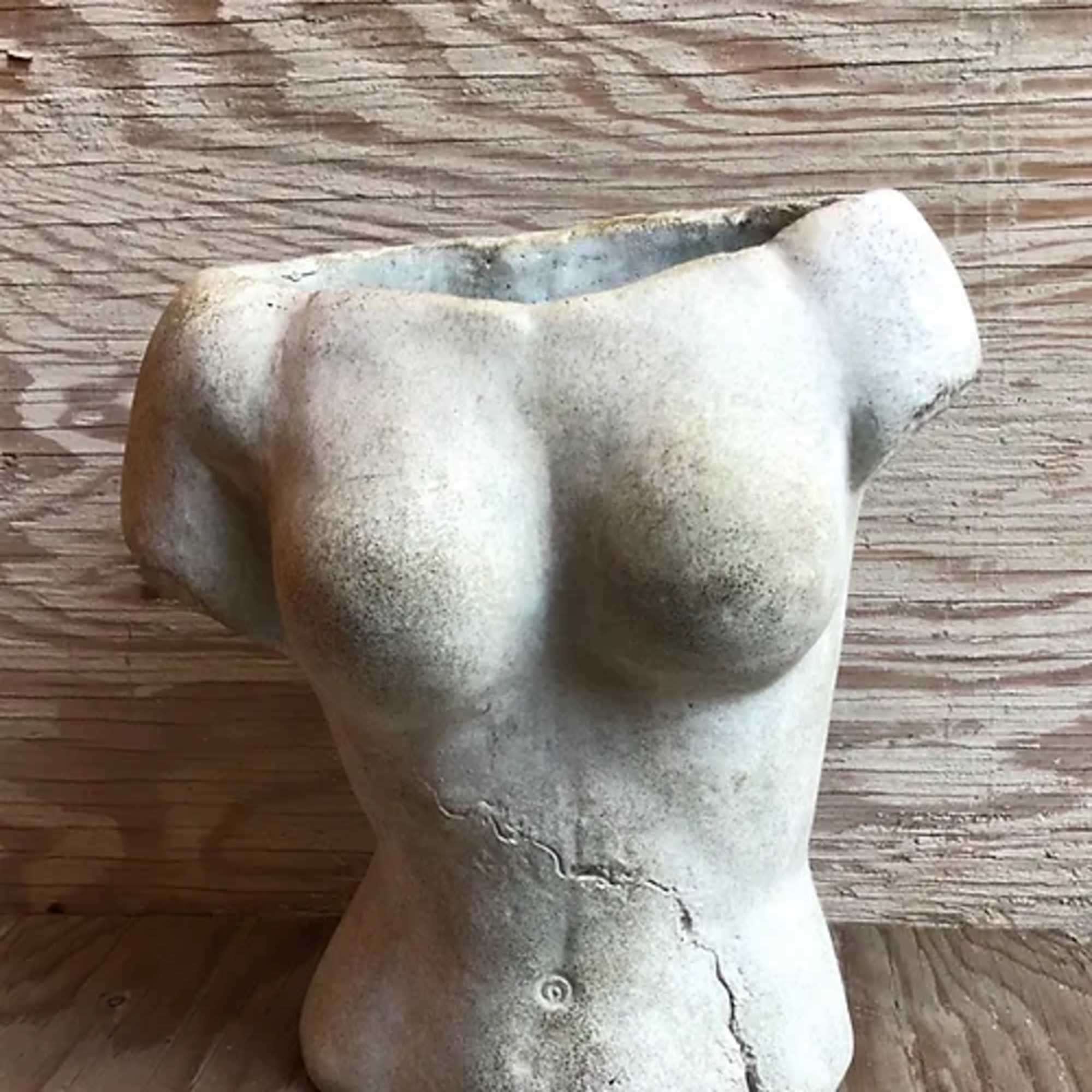 Torso-shaped ceramic planter on a wooden surface