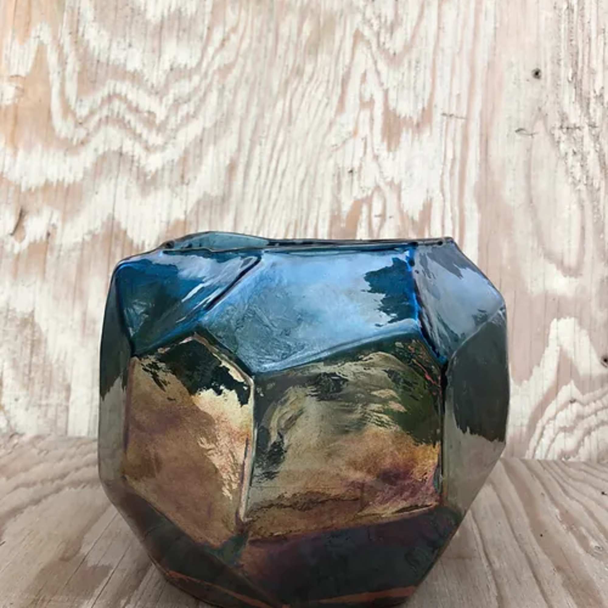 Faceted iridescent glass vase on a wooden surface