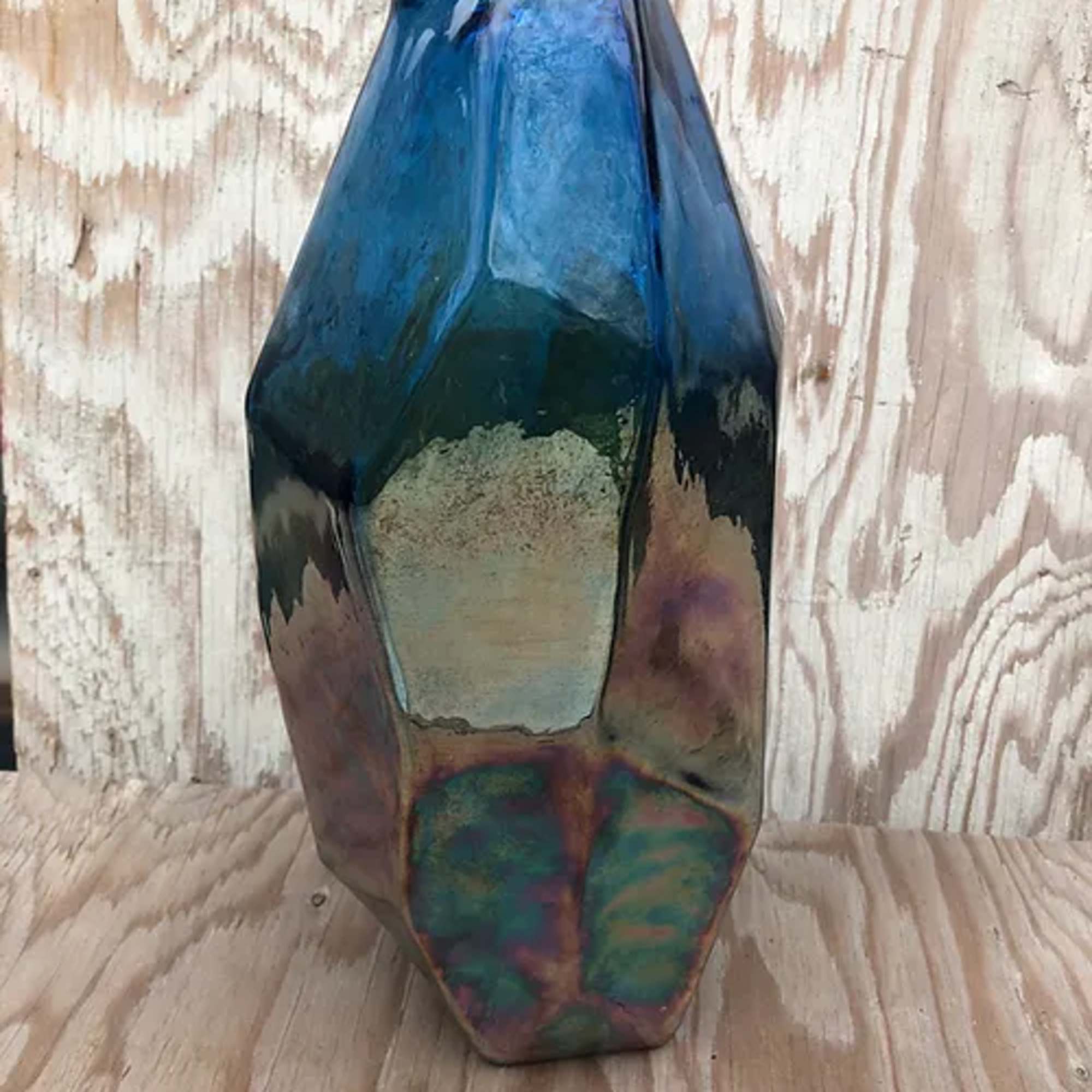 Blue iridescent geometric glass vase on a wooden surface