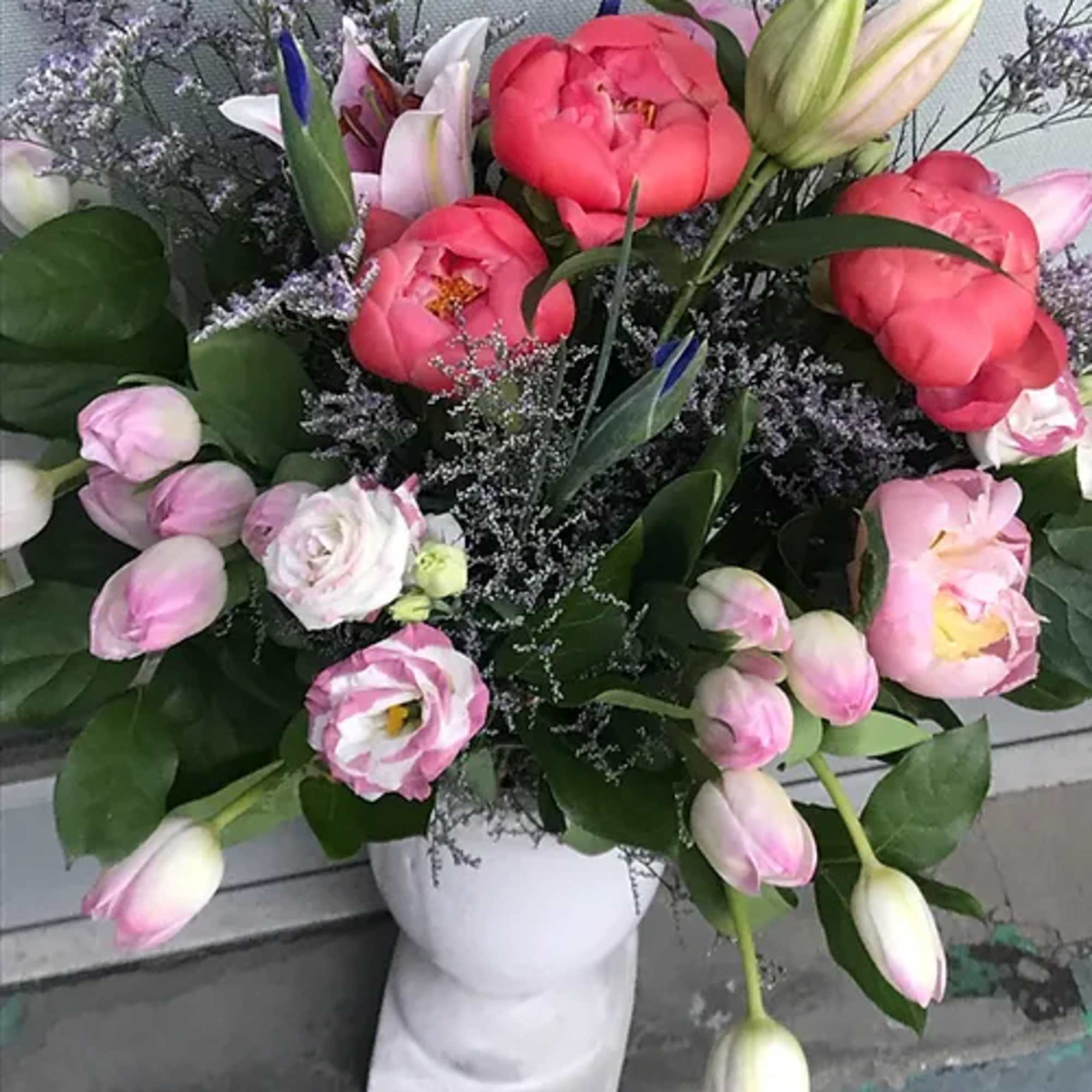 Bouquet of pink peonies and tulips in a white vase