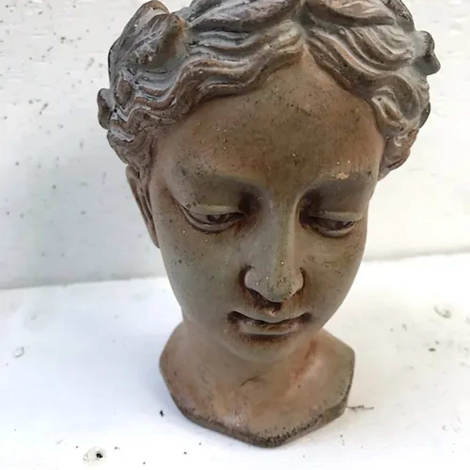Weathered stone bust of a woman with closed eyes
