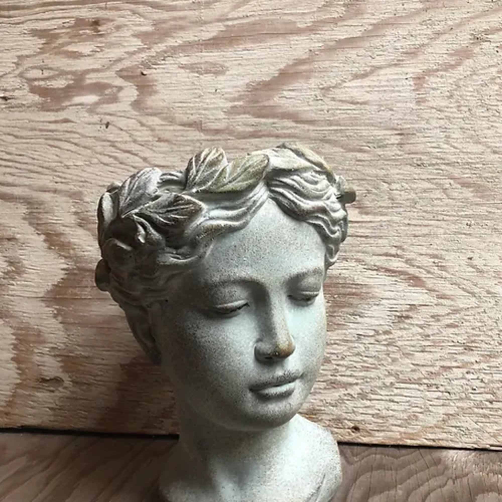 Stone-colored decorative bust of a woman with closed eyes