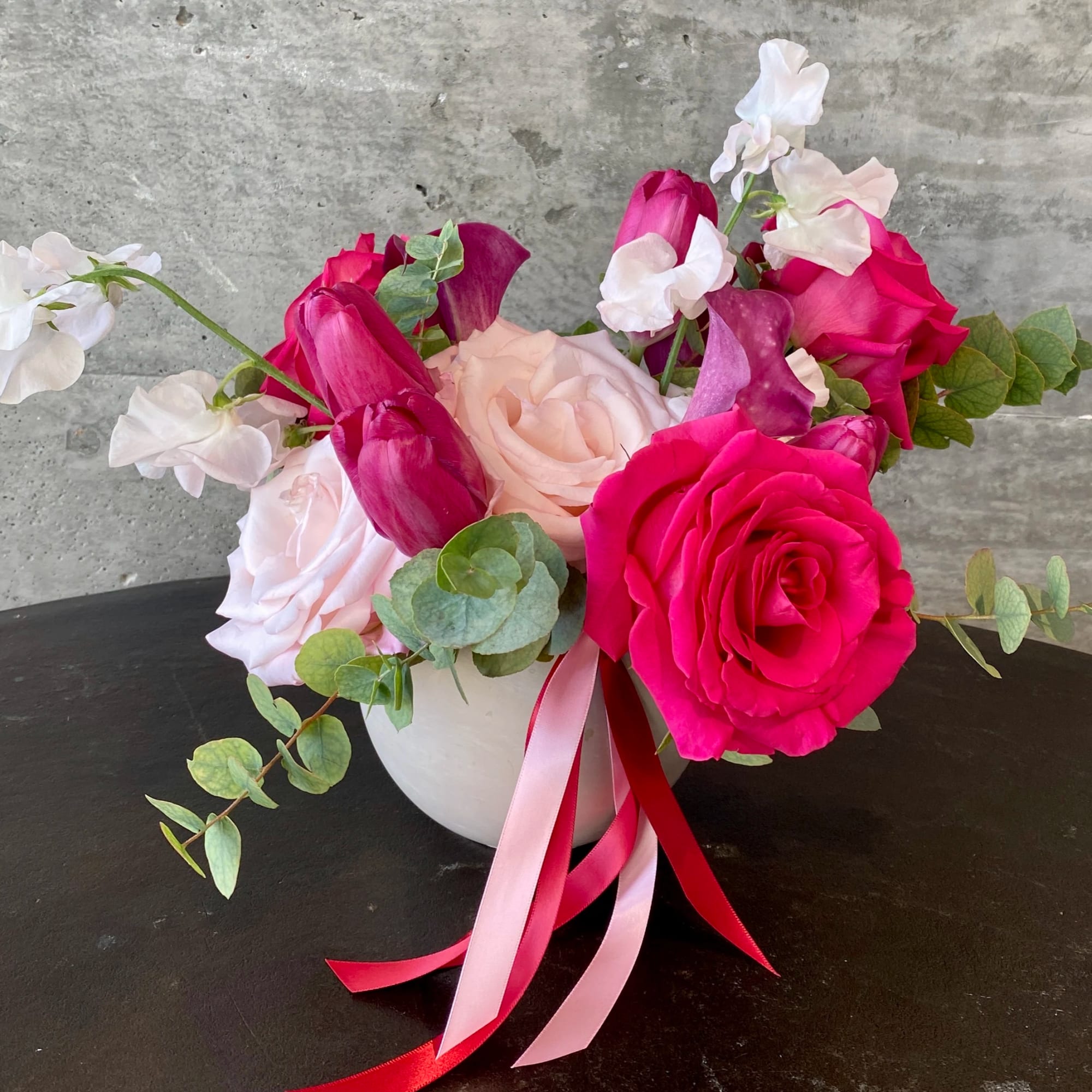Pink and white rose bouquet in a white vase with ribbon