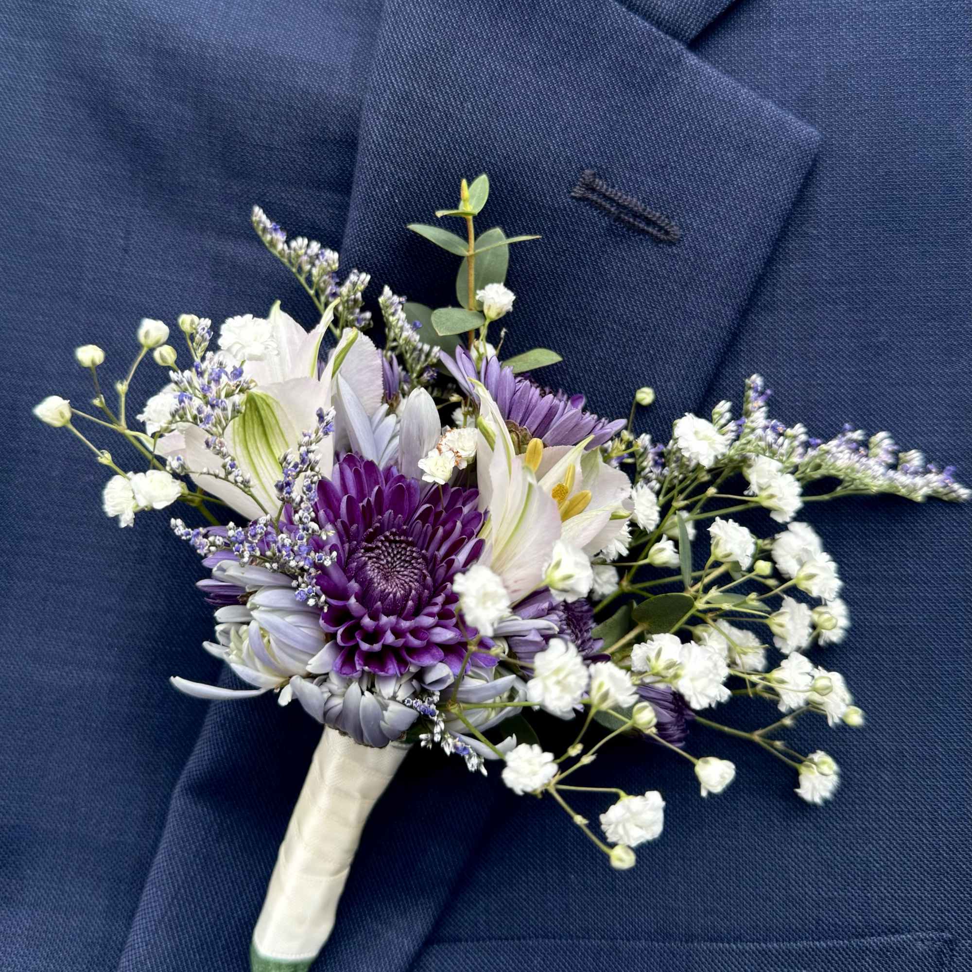 Purple and white boutonniere pinned to a navy suit jacket