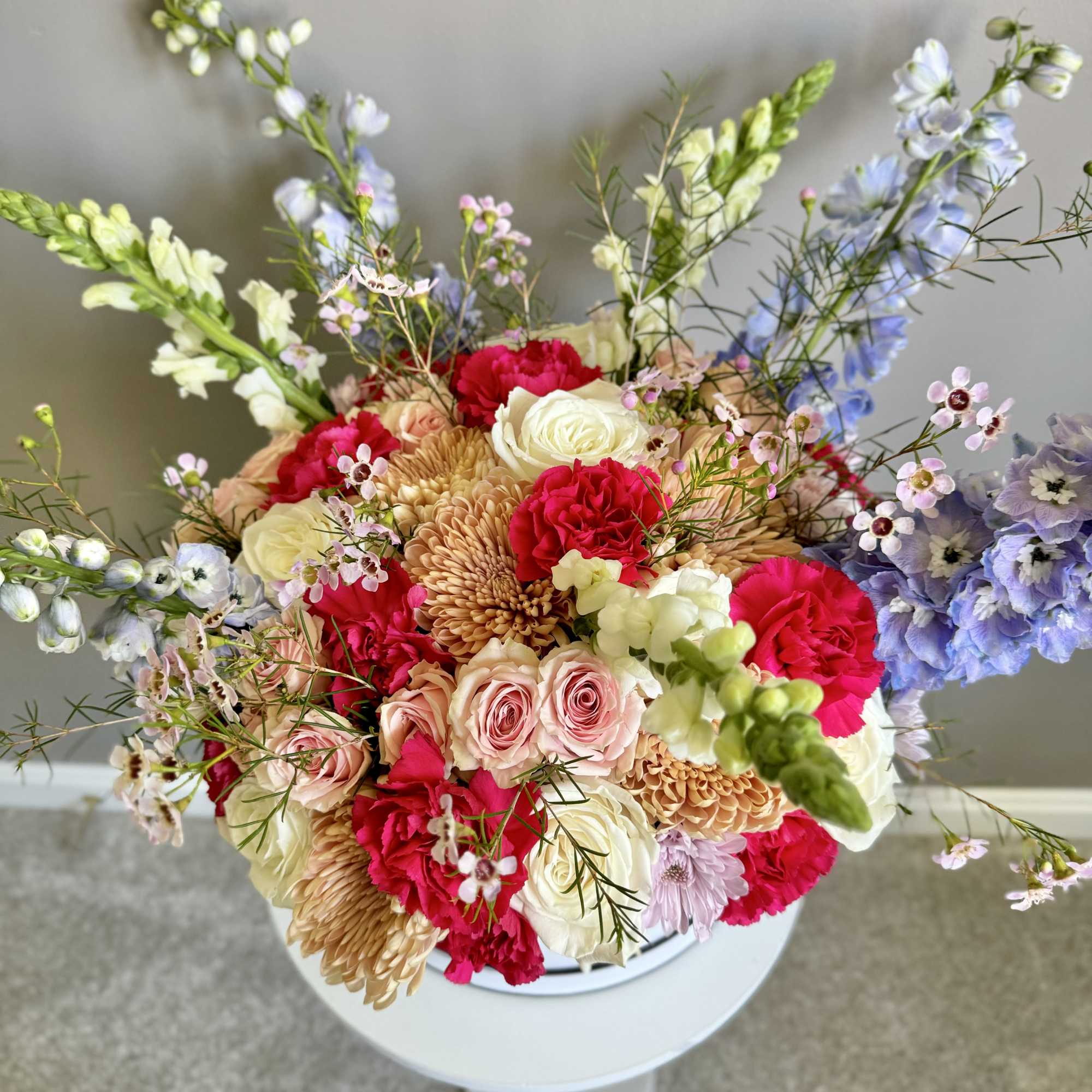 Colorful mixed flower arrangement in a white pedestal vase