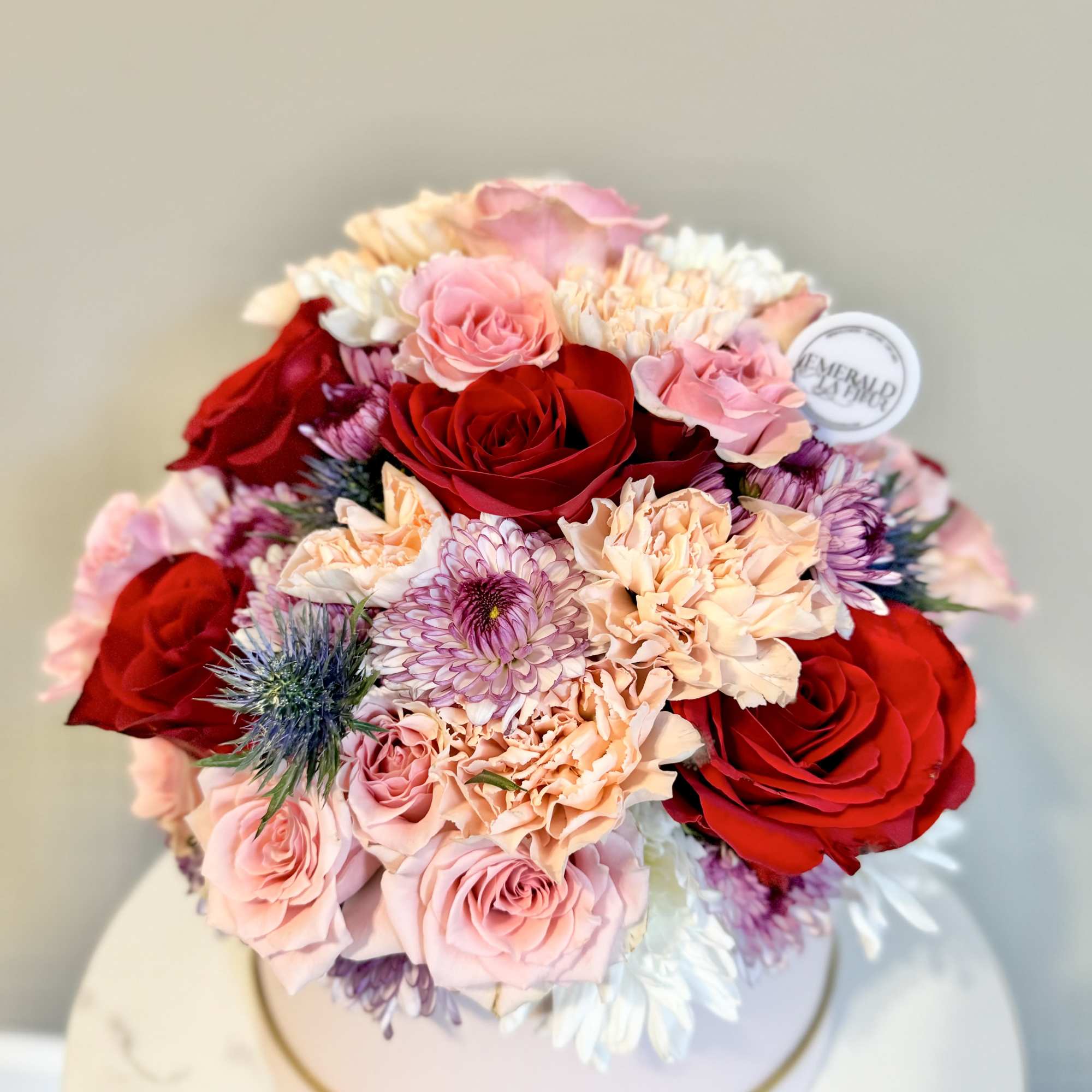 Round bouquet of red and pink roses with peach and purple blooms