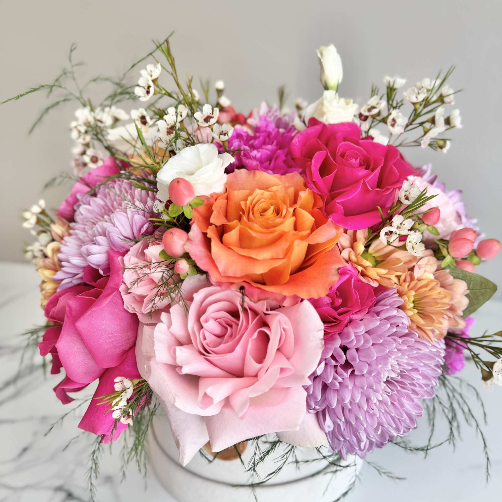 Colorful bouquet of roses and chrysanthemums in a white hat box