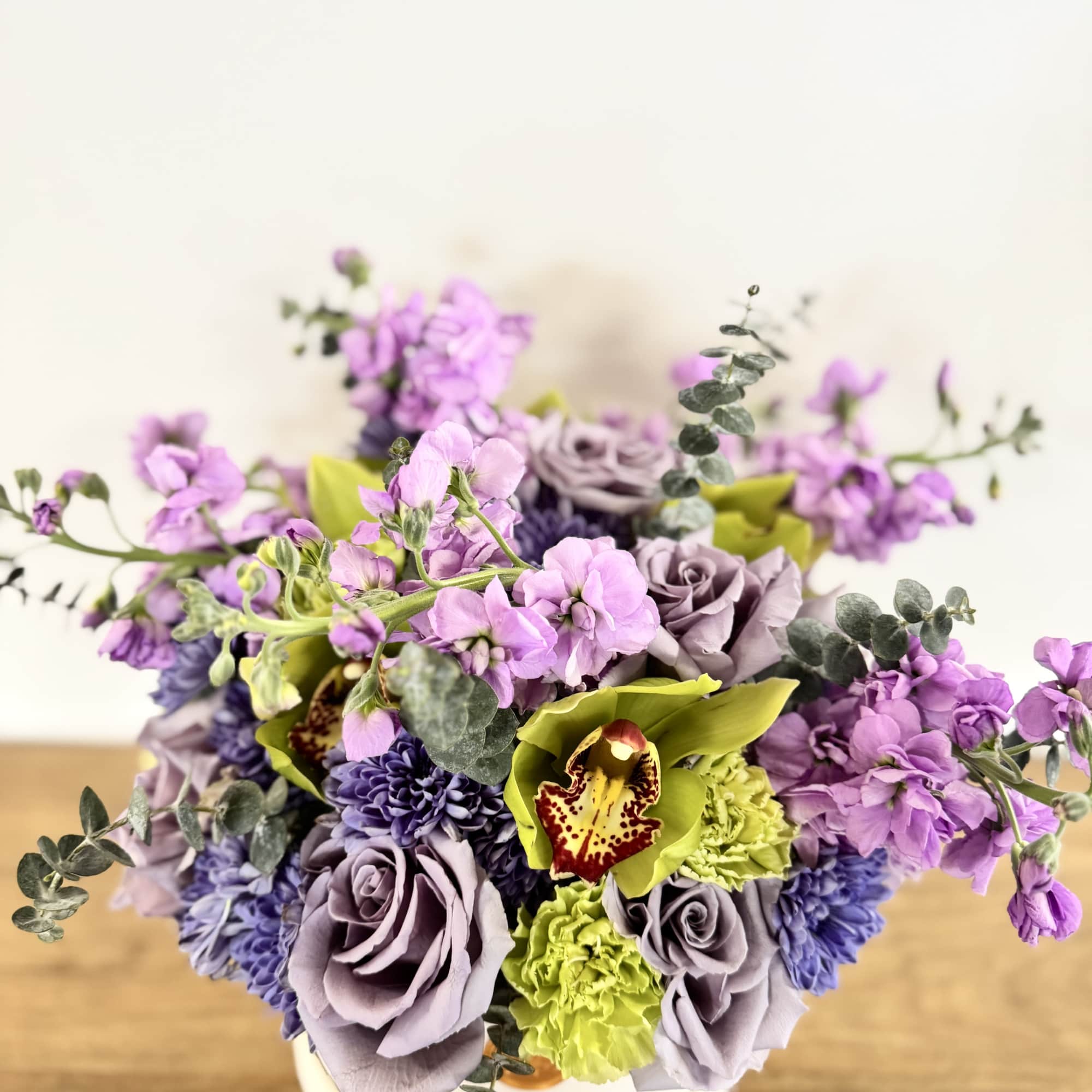 Lavender and green floral arrangement in a white vase