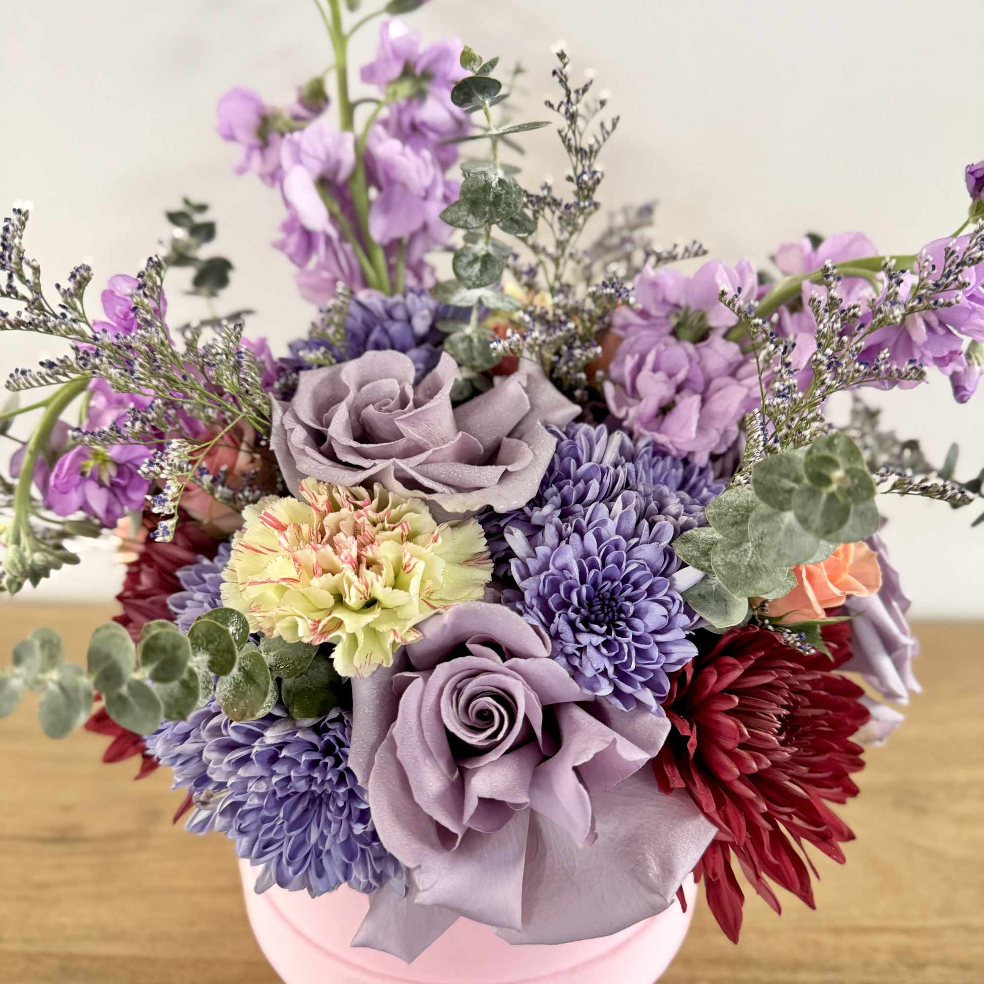 Mixed bouquet in a pink round box with lavender and purple blooms