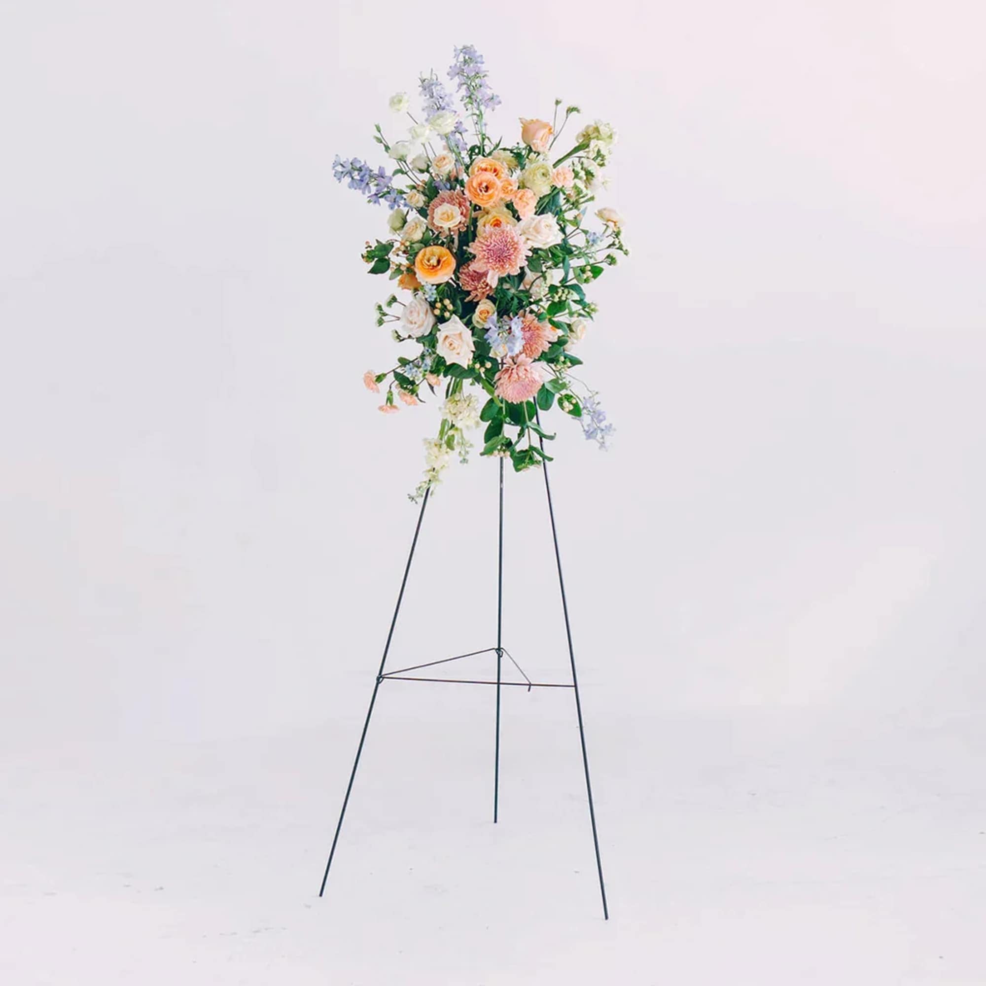 Tall pastel floral arrangement on a black metal stand
