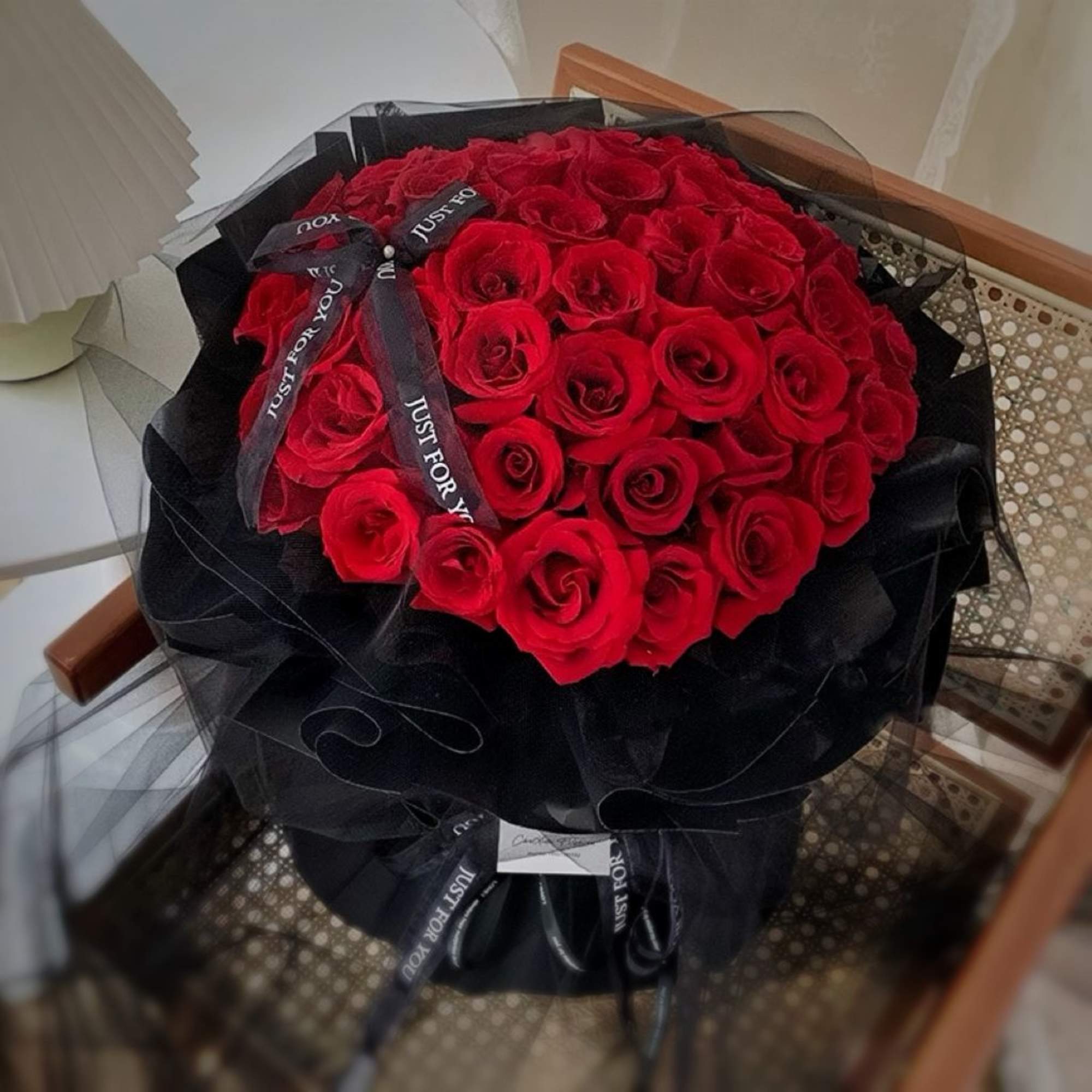 Bouquet of red roses wrapped in black paper with a ribbon
